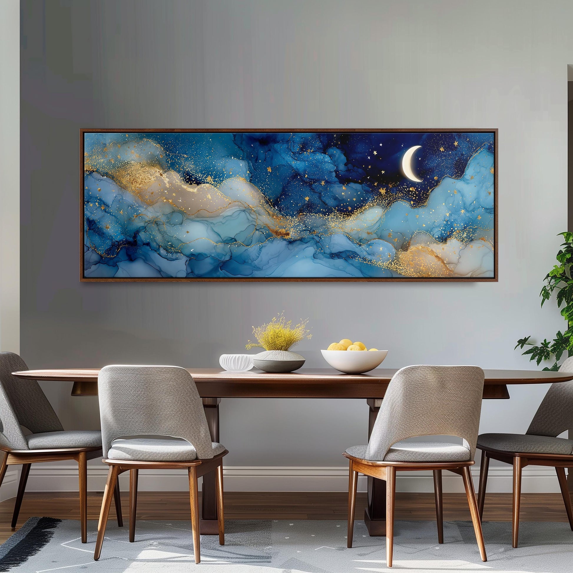 a large, framed painting of a night sky with a crescent moon and stars, hanging on a wall above a wooden dining table with four chairs.