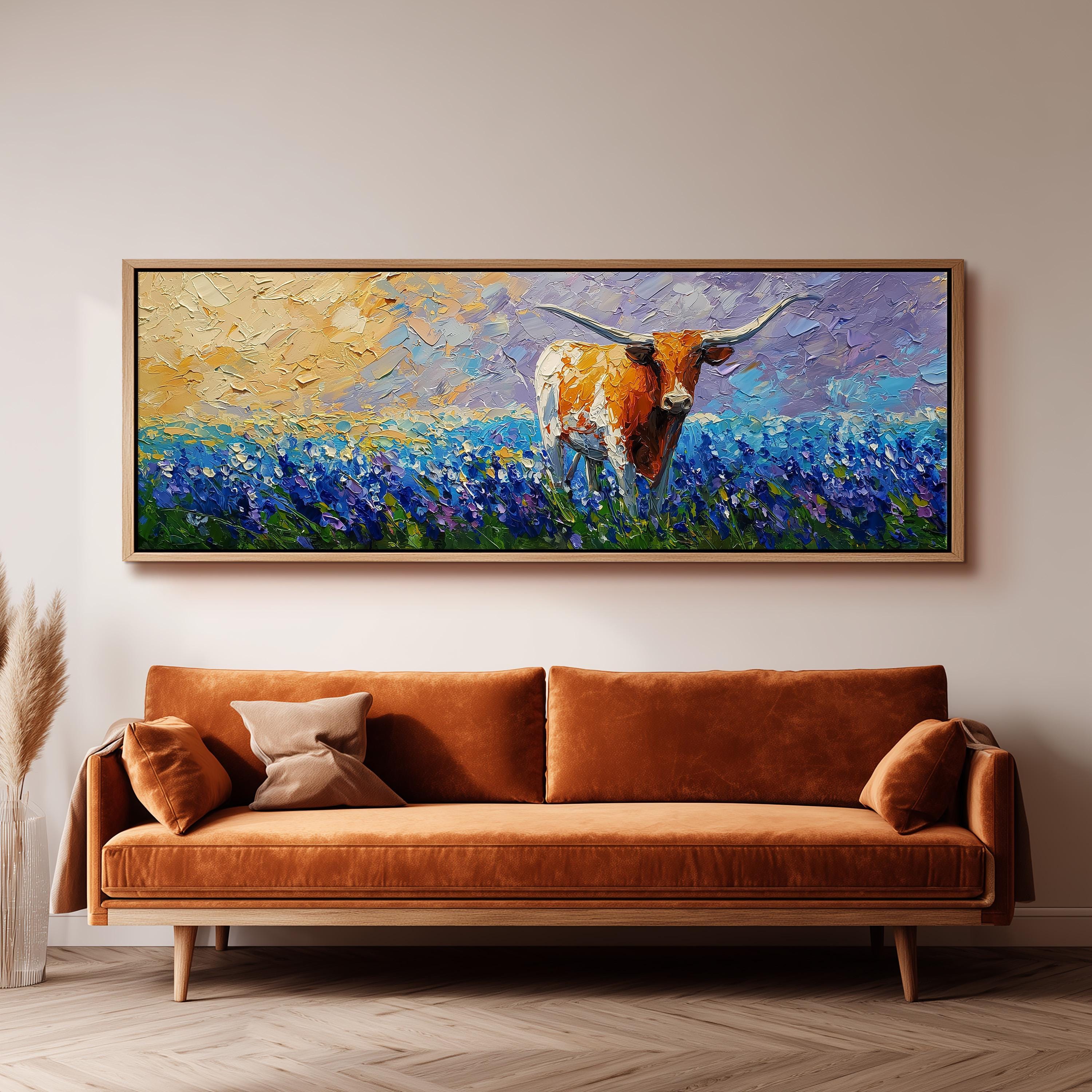 a large painting of a cow in a field of flowers hanging on a wall above a brown sofa.