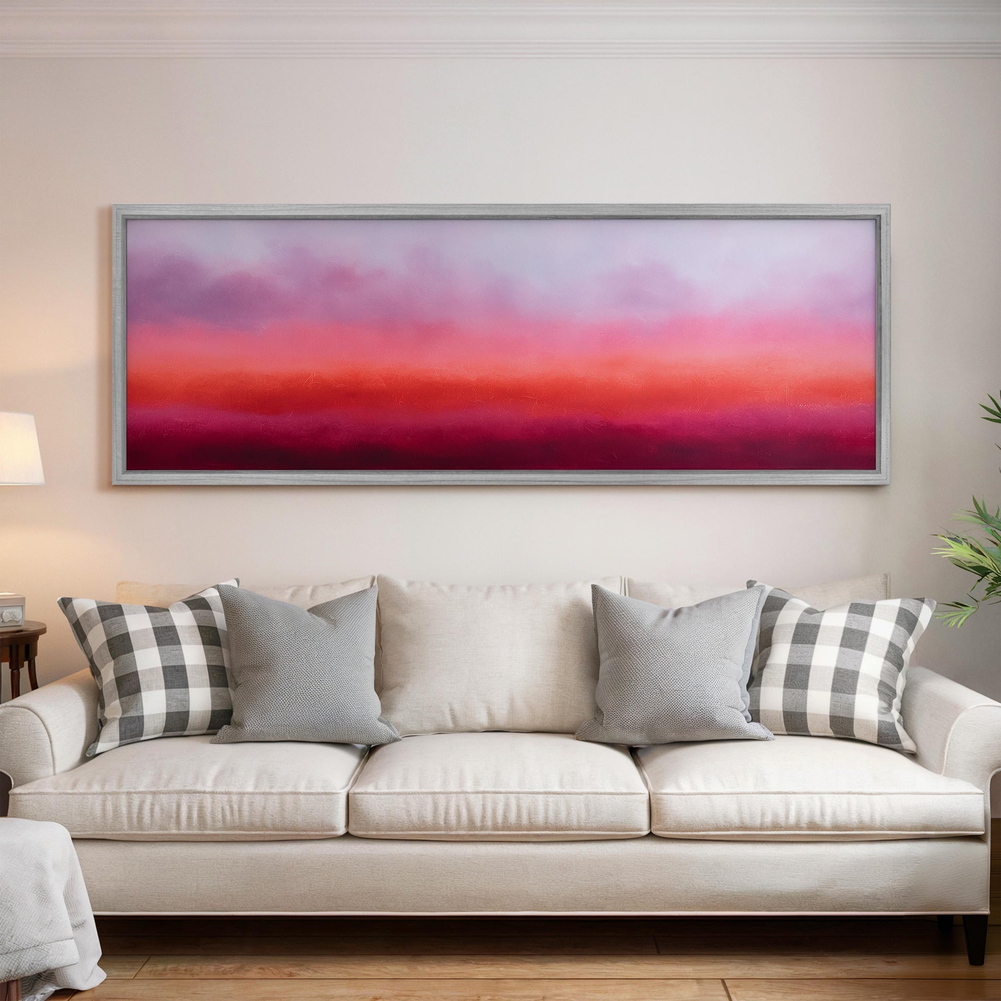 a large, rectangular painting hanging on a white wall above a white couch with gray and white patterned pillows.