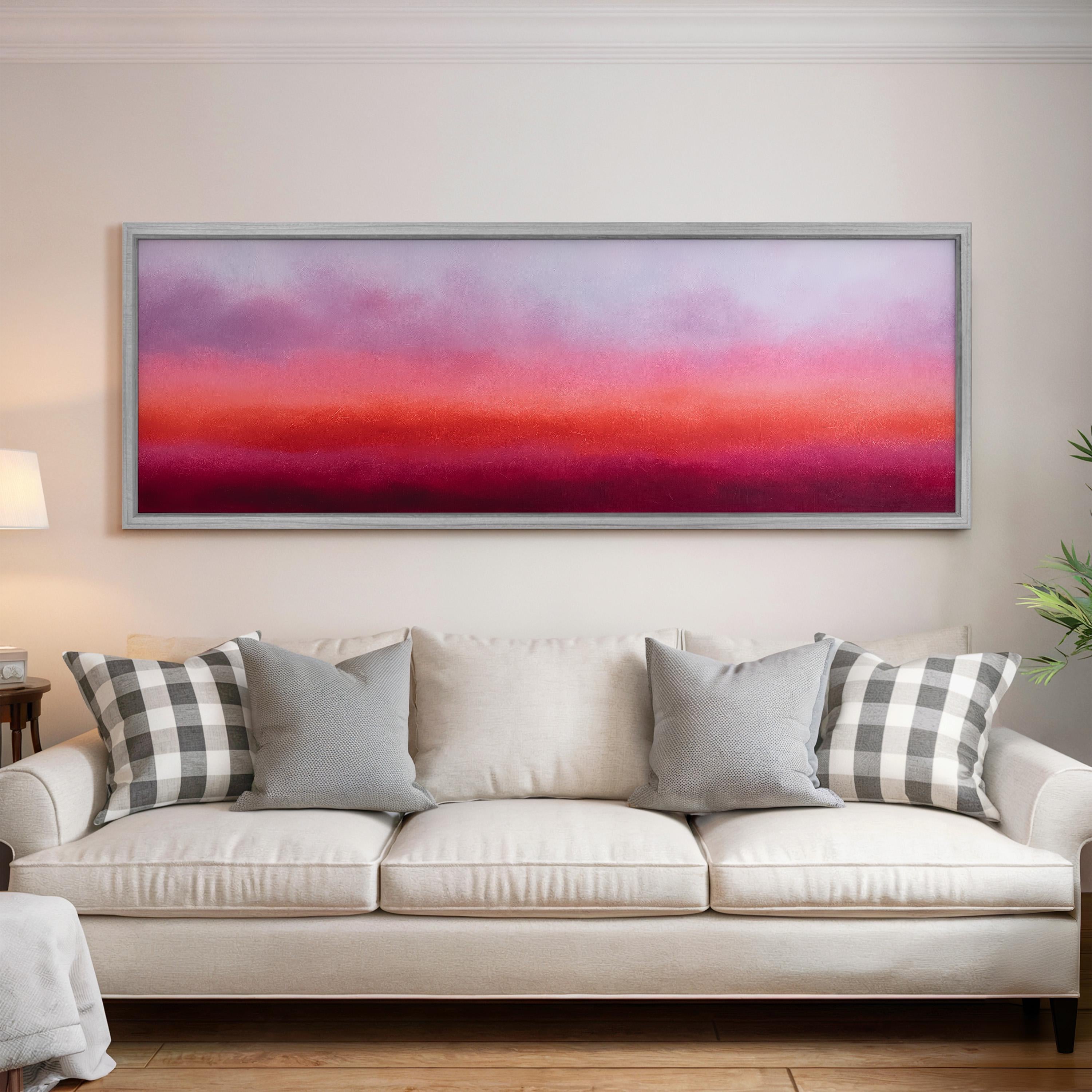 a large, rectangular painting hanging on a white wall above a white couch with gray and white patterned pillows.