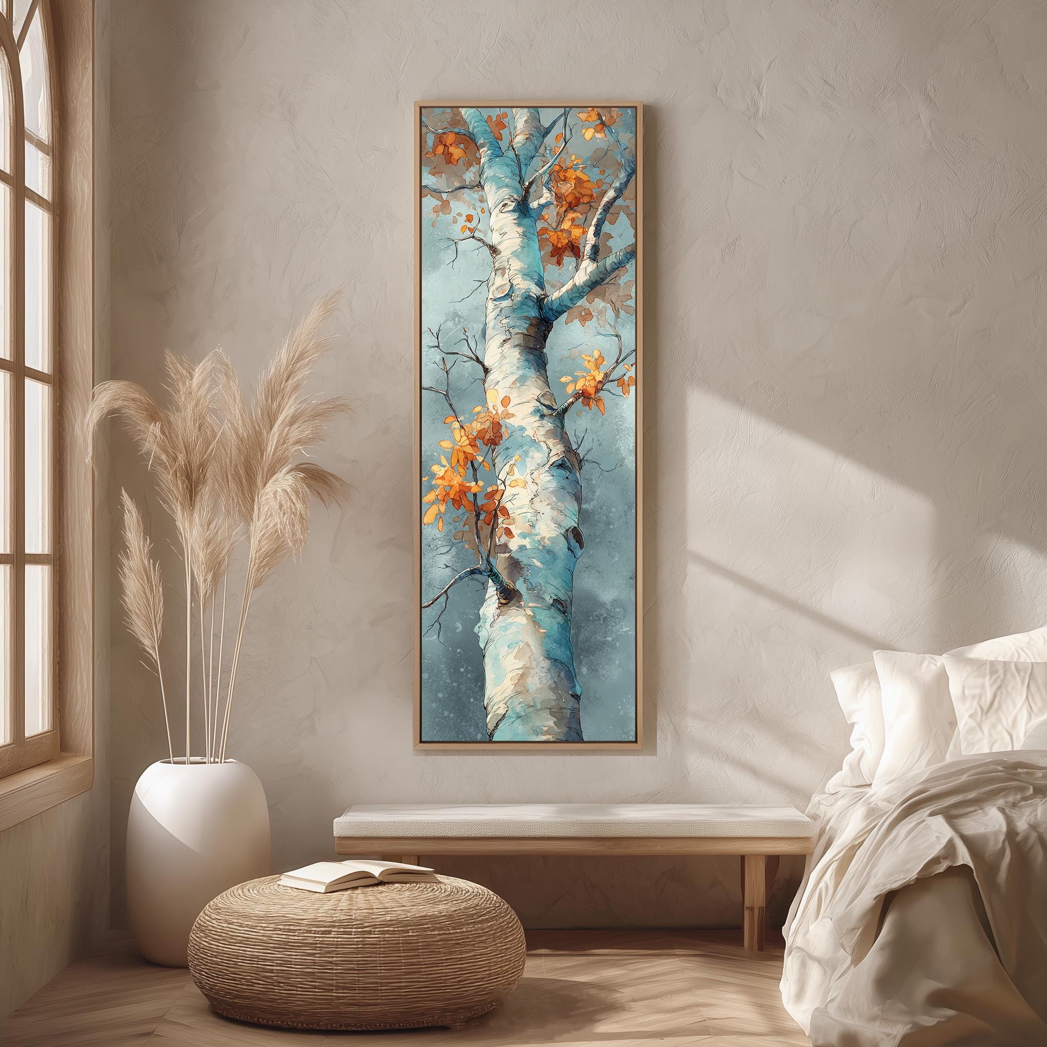 a large painting of a tree with orange leaves hanging on a wall in a room with a bed, a wicker ottoman, and a potted plant.