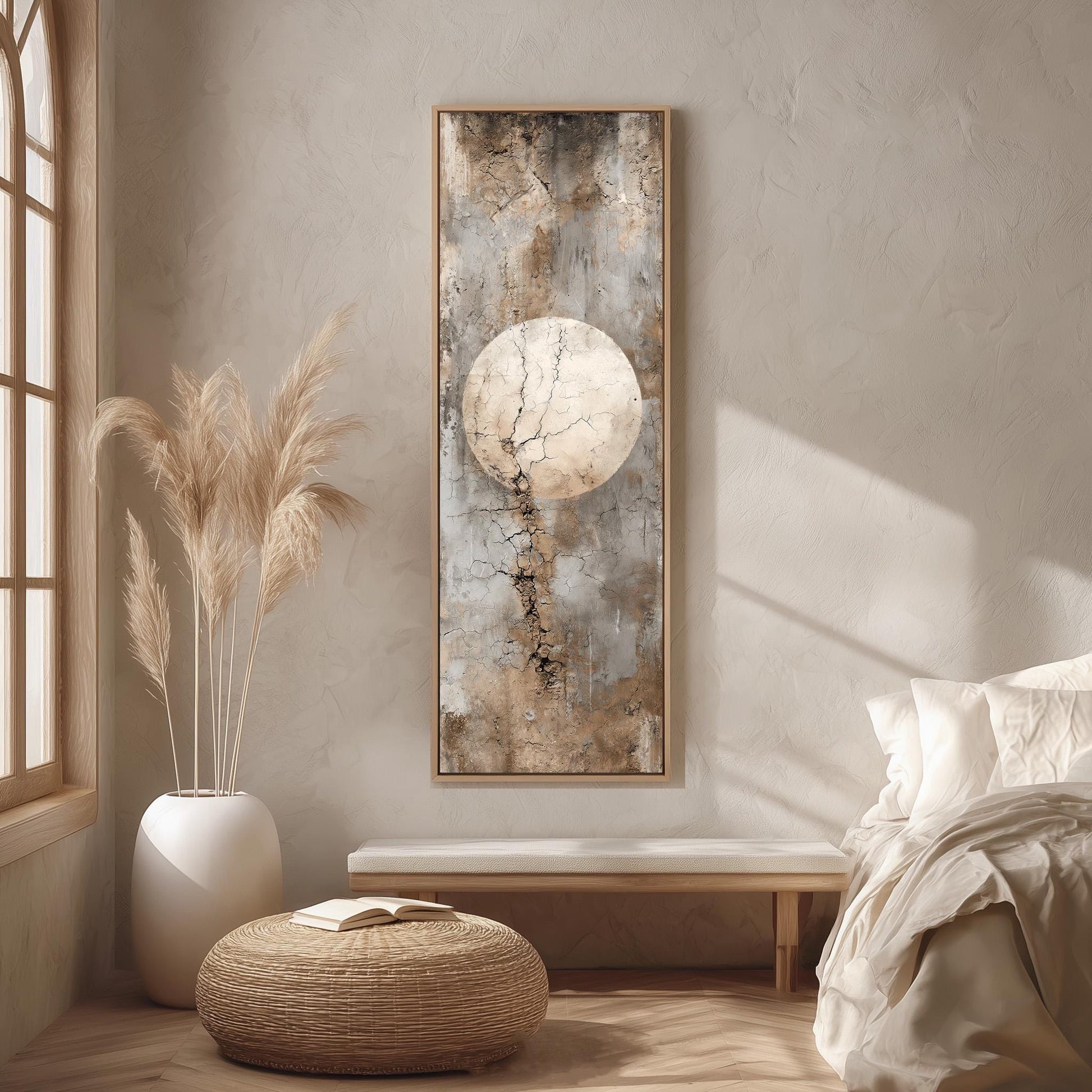 a serene and minimalist bedroom with a large window, a bed with white bedding, a wicker ottoman, and a framed artwork featuring a large circular design on the wall.