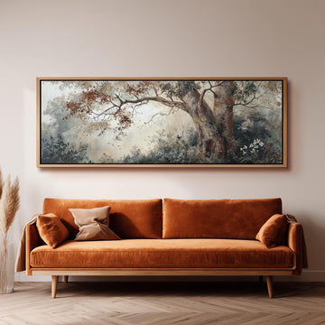 a large, framed painting of a tree with a forest scene hanging on a wall above a brown sofa with orange cushions.