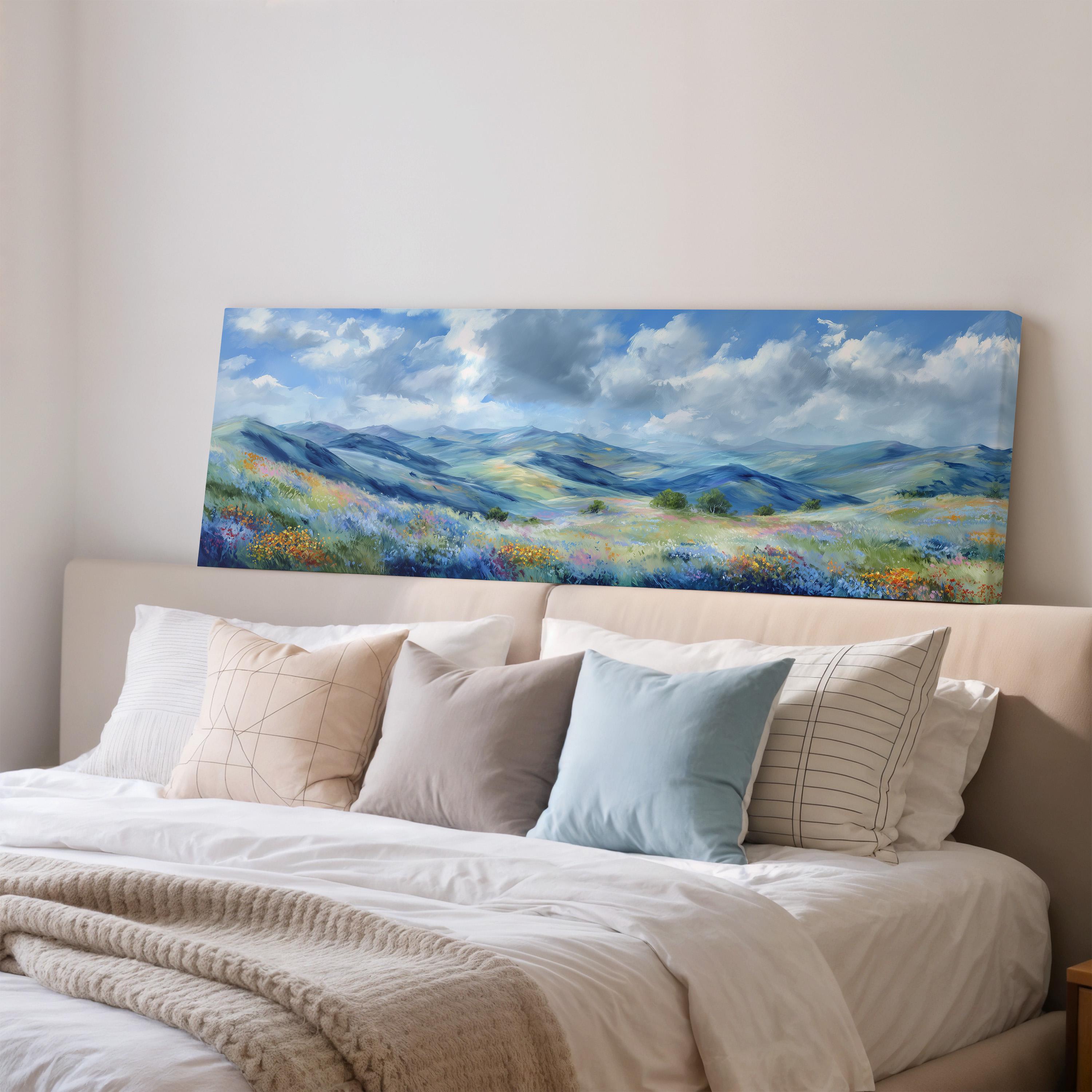 a large landscape painting hanging on a wall above a bed with white pillows and a gray blanket.
