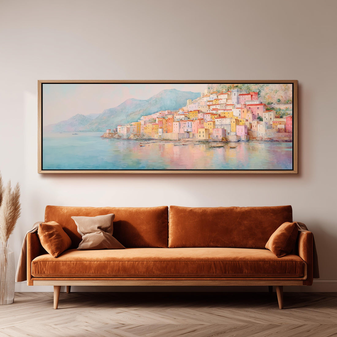 a large, colorful painting of a coastal town hanging on a wall above a brown sofa.