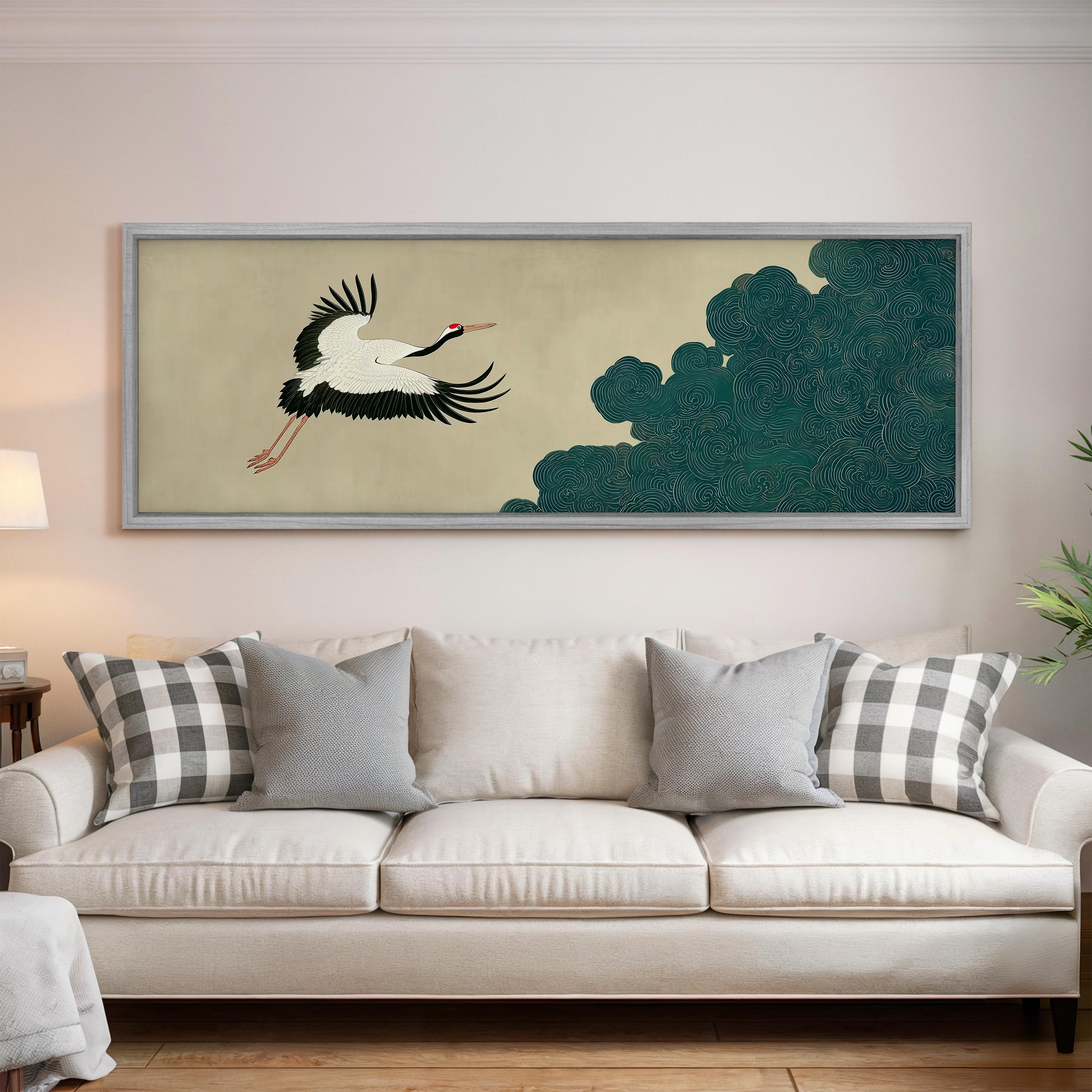 a large framed artwork of a crane in flight, hanging on a wall above a white sofa with patterned throw pillows.