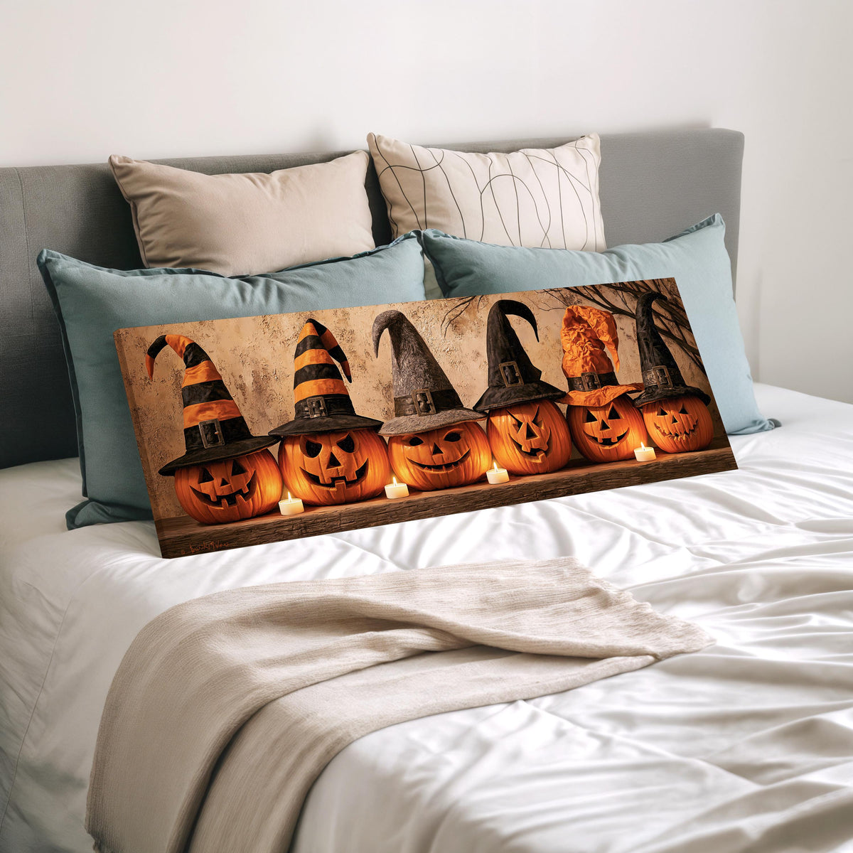 Jack-o'-lanterns wearing witch hats by candlelight wide panoramic canvas print laid on a bed to show its size
