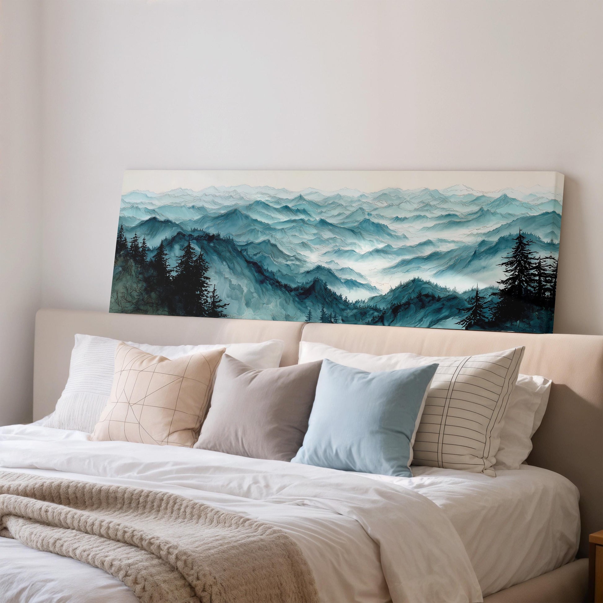 a large landscape painting hanging on a wall above a bed with white pillows and a gray blanket.