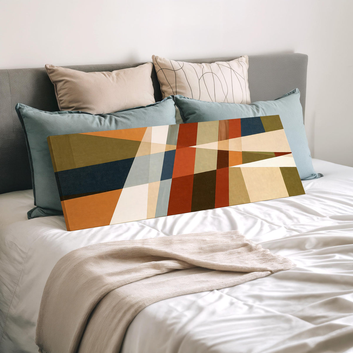 Rust and navy diagonal color blocks wide panoramic canvas print laid on a bed to show its size