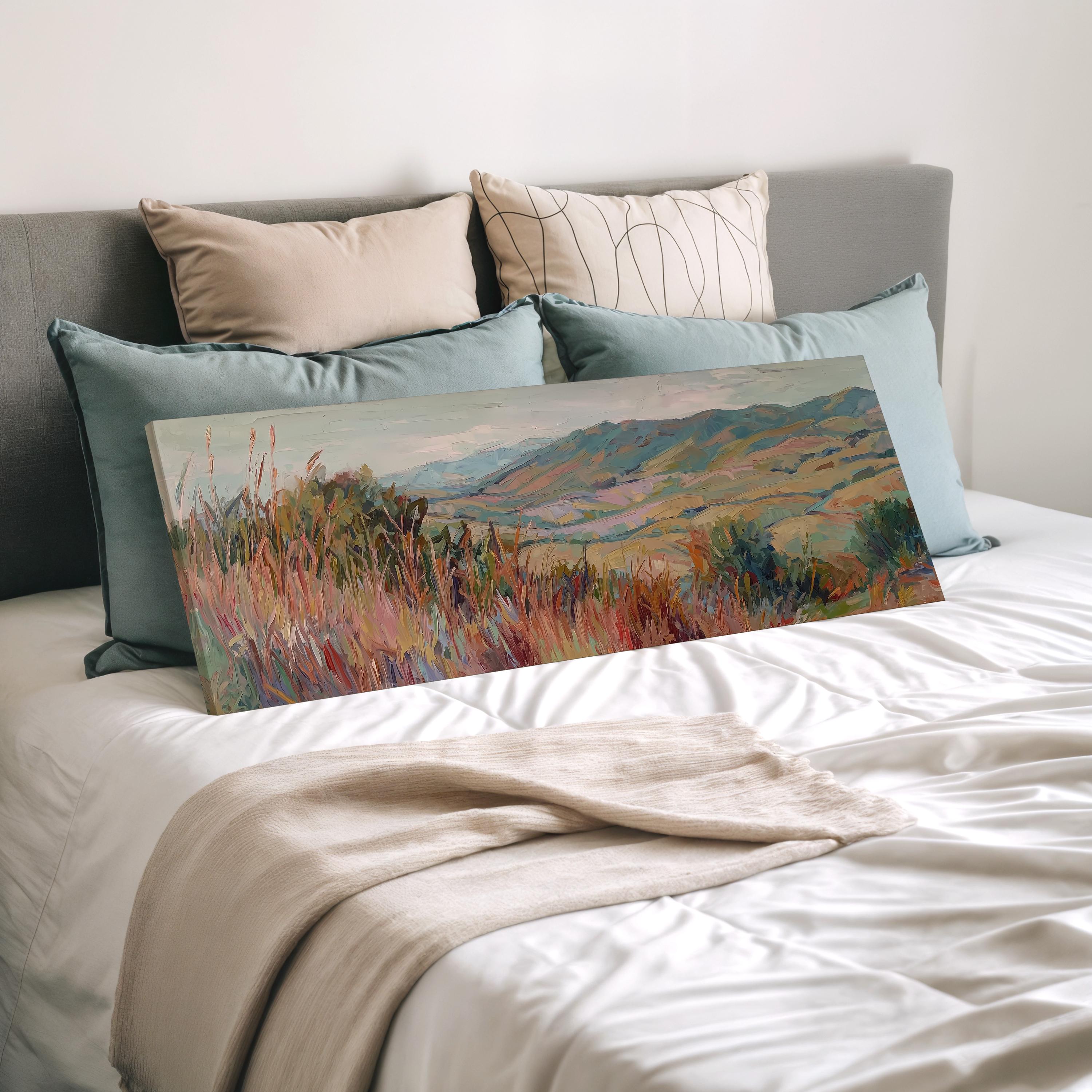 a large landscape painting displayed on a bed, surrounded by pillows.