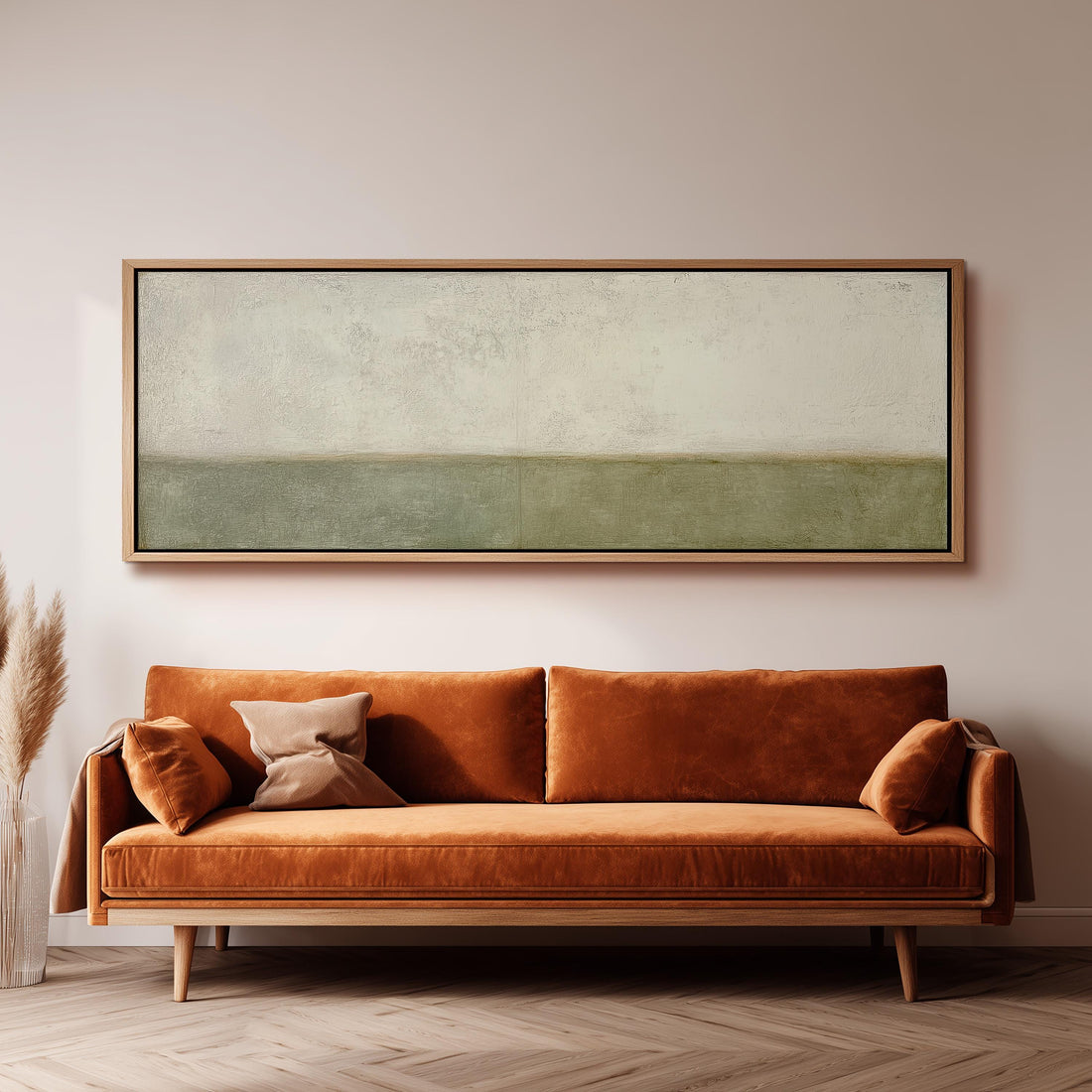a large, rectangular painting hanging on a wall above a brown sofa with orange cushions.