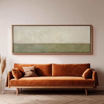 a large, rectangular painting hanging on a wall above a brown sofa with orange cushions.