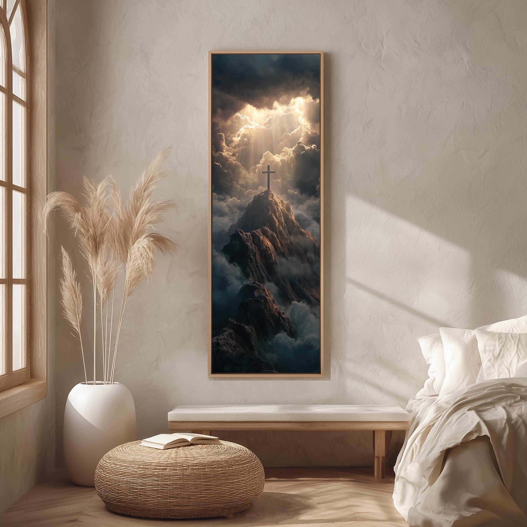 a serene bedroom scene with a large framed picture of a mountain landscape hanging on the wall, featuring a cross on top of the mountain. The room has a white bed, a wicker ottoman, and a potted plant, creating a calm and peaceful atmosphere.