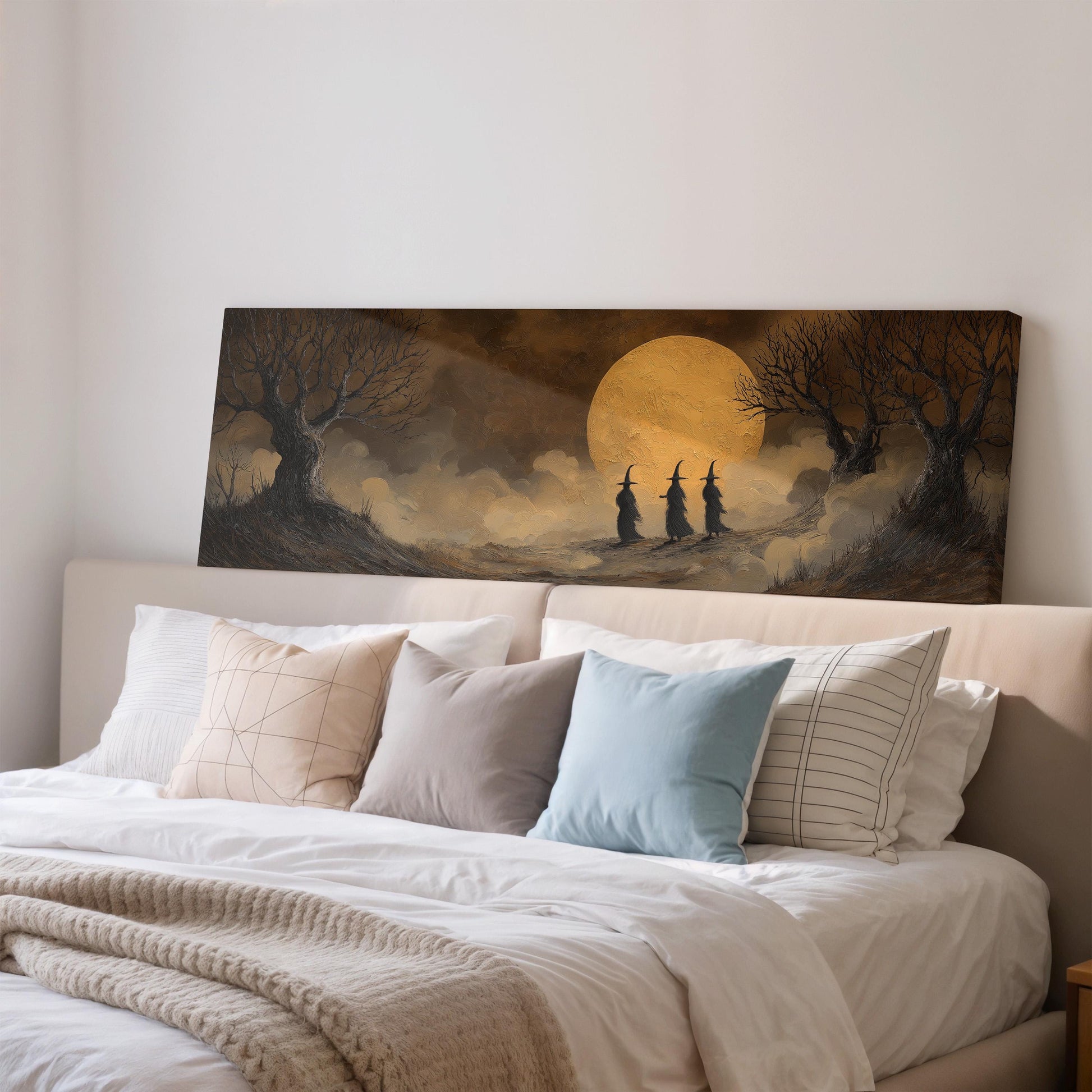 a bedroom scene with a large painting of a moonlit landscape hanging on the wall above a bed with white pillows and a gray blanket.