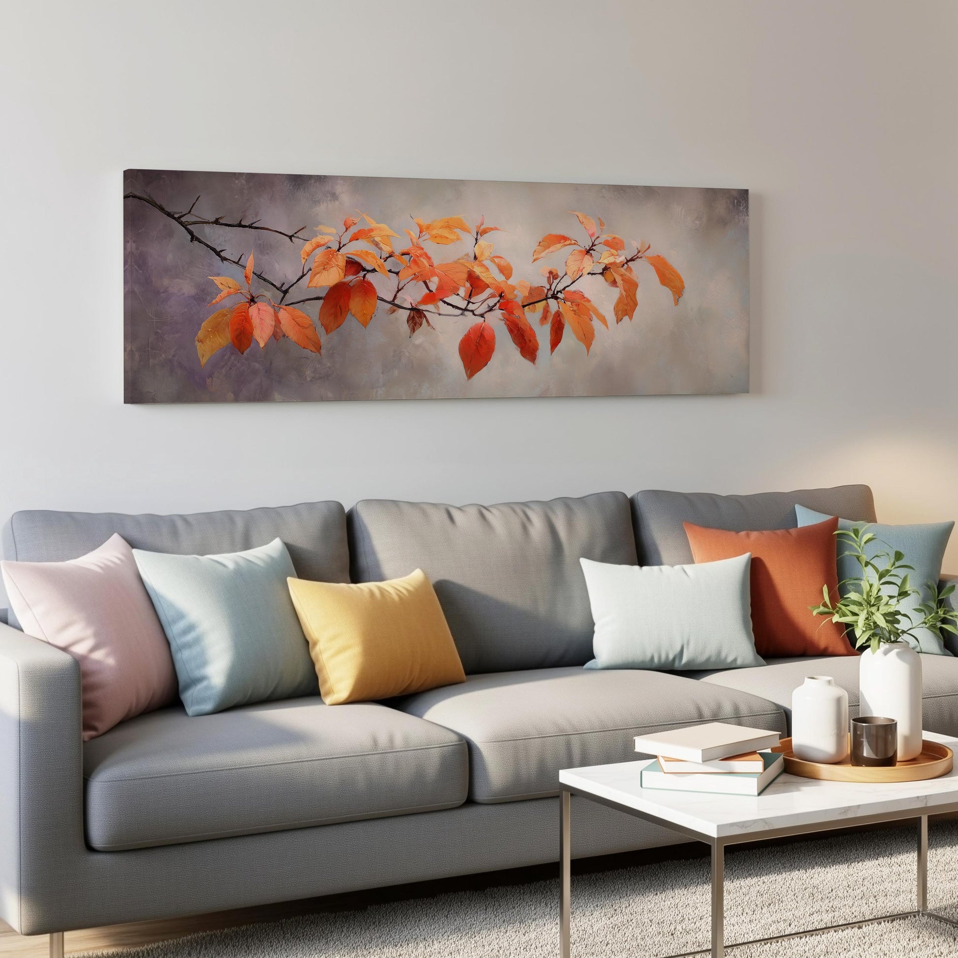 a gray couch with colorful throw pillows, a coffee table, and a painting of orange leaves hanging on the wall above the couch.