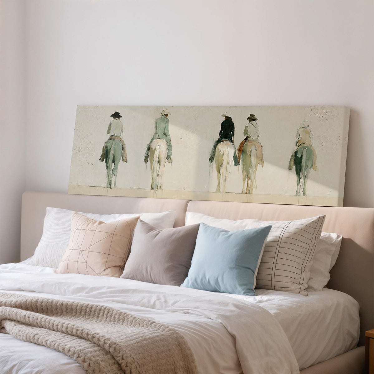 Riders on horseback seen from behind wide panoramic canvas print above a bed in a bedroom