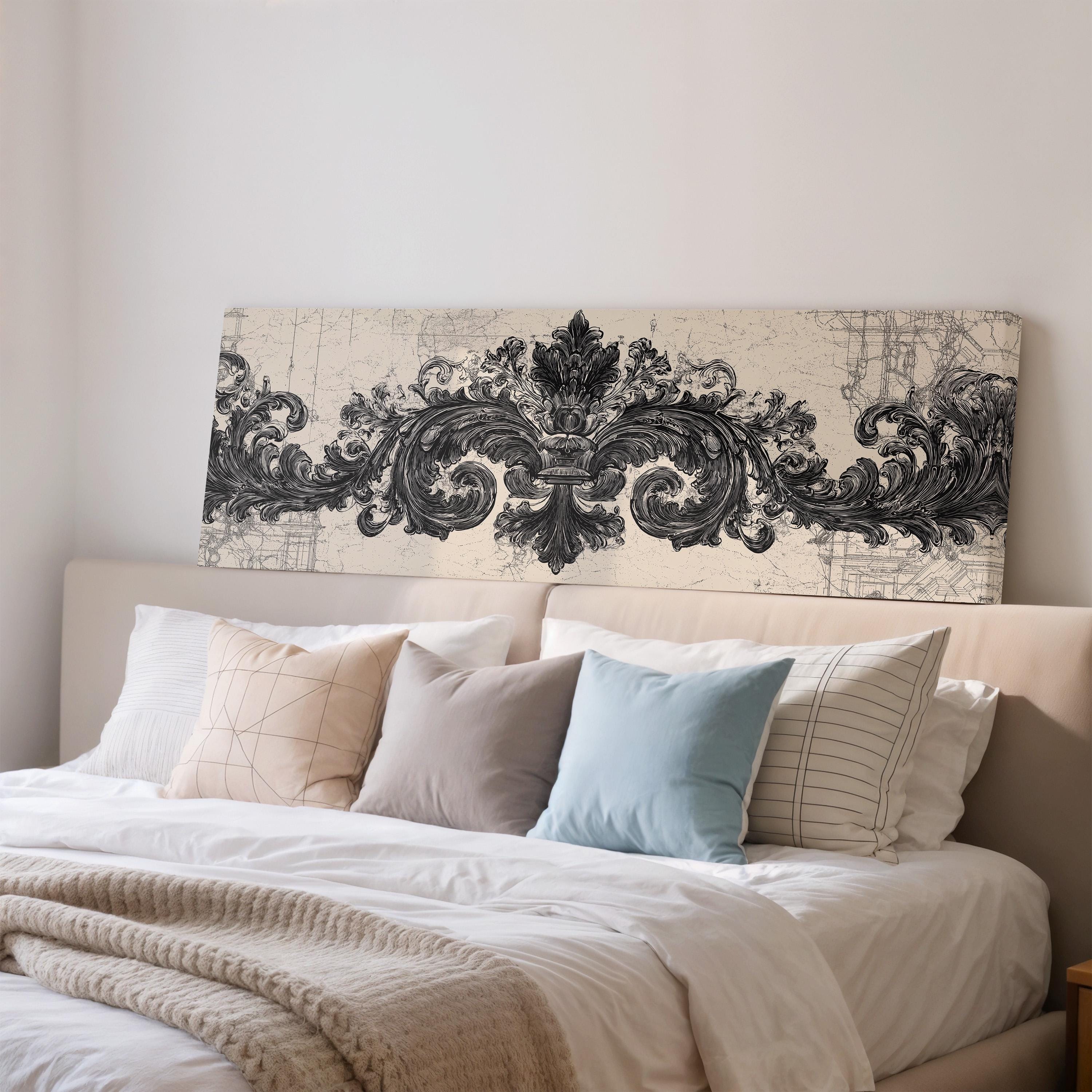 a large bed with a white comforter and several pillows, including a blue pillow and a striped pillow. Above the bed, there is a decorative headboard with an ornate, black and white design.
