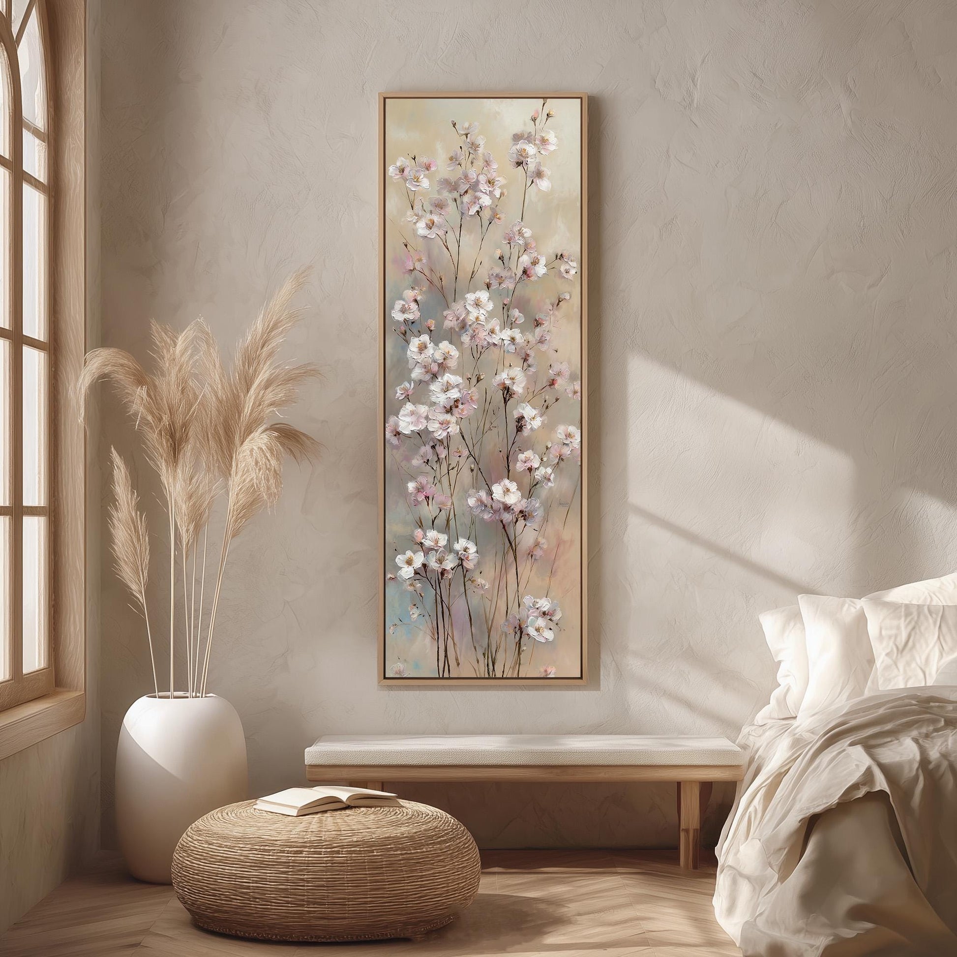a serene and cozy bedroom scene, featuring a large floral painting hanging on the wall, a white bed with a white pillow, a white vase with tall potted plants, and a woven ottoman in front of the bed.