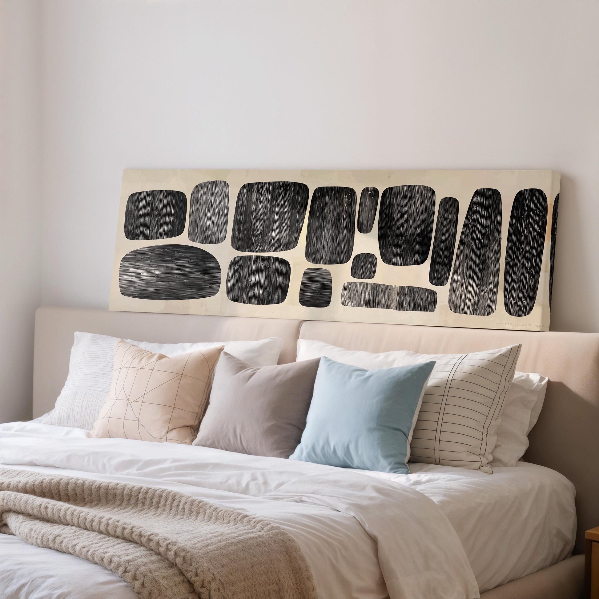 a well-made bed with a variety of pillows and a large abstract artwork displayed above it.
