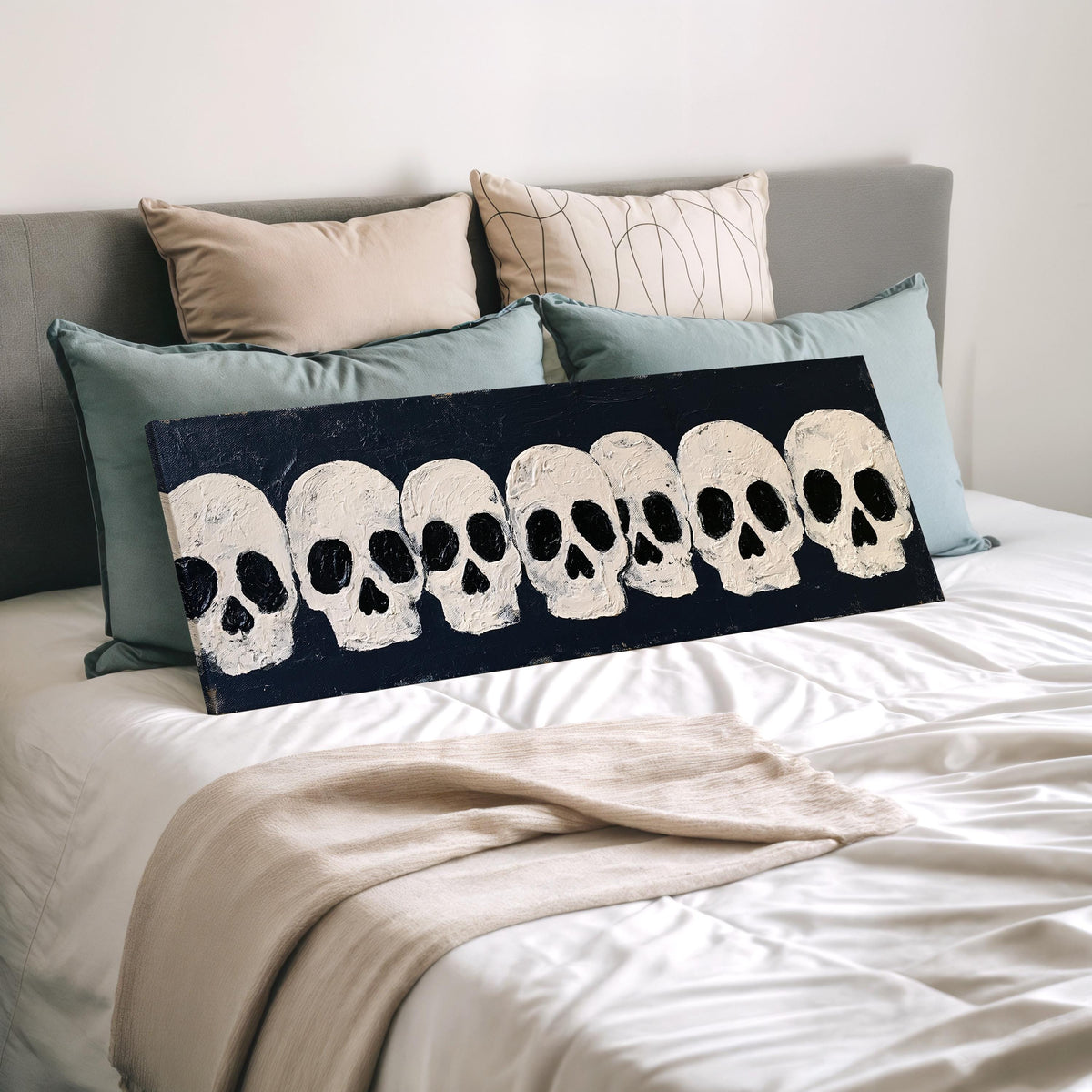 Row of white skulls on navy wide panoramic canvas print laid on a bed to show its size