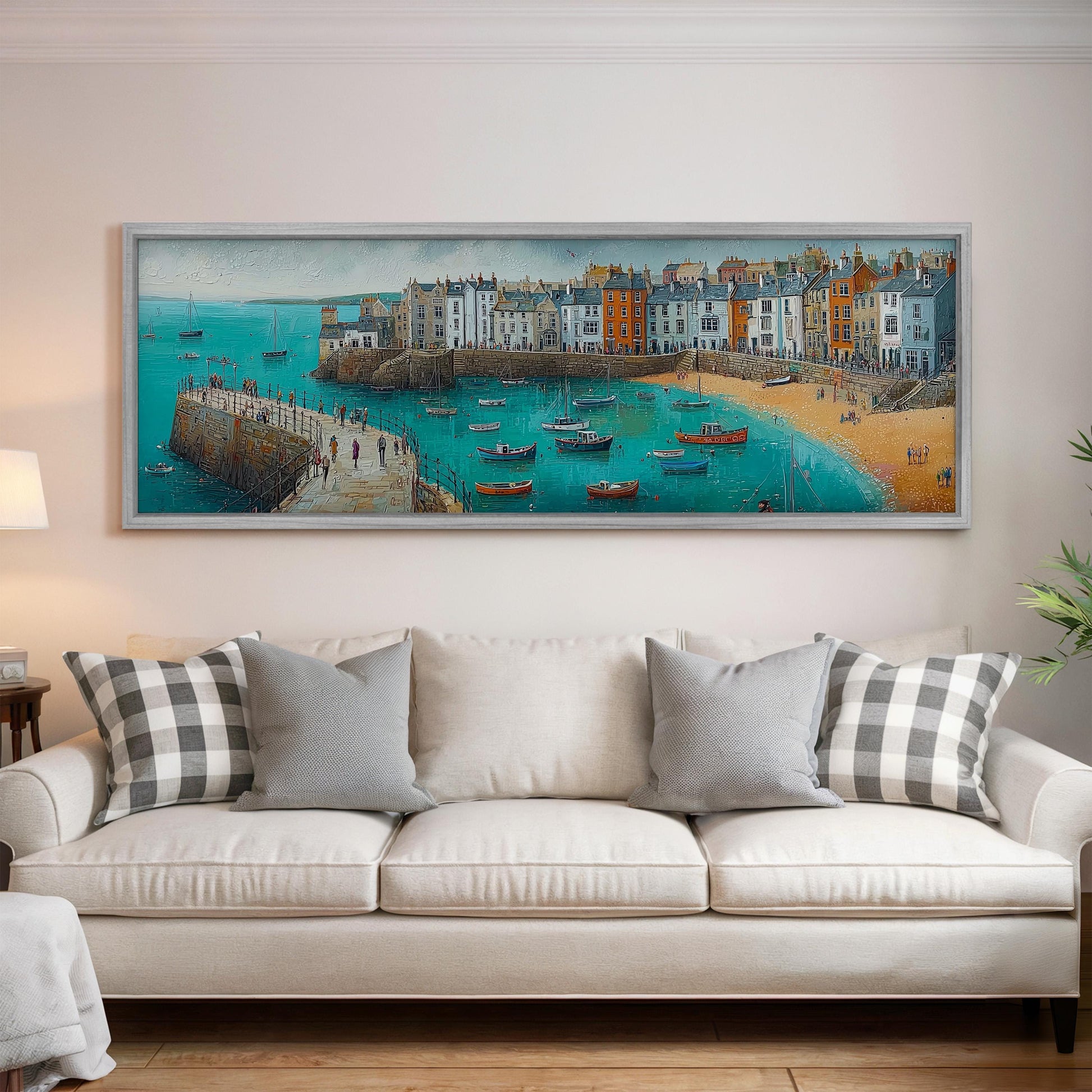 a large, framed painting of a coastal town with boats in the water, hanging on a wall above a white couch with patterned throw pillows.