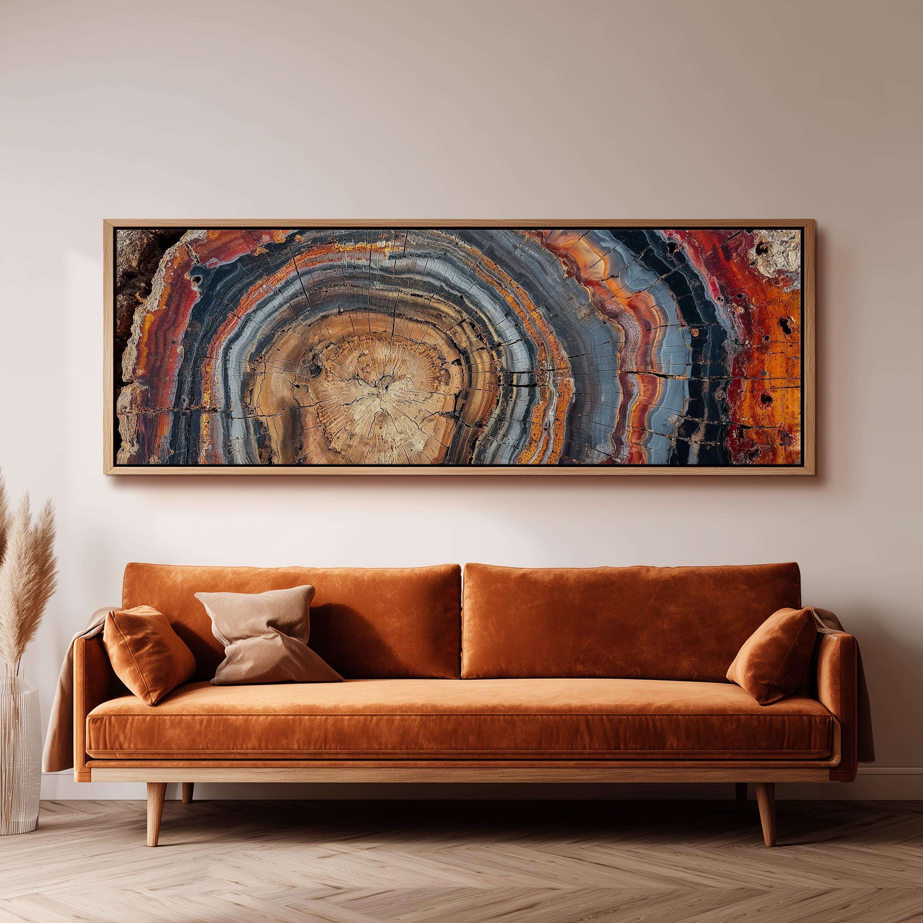 a large, abstract painting hanging on a wall above a brown sofa with a wooden frame.
