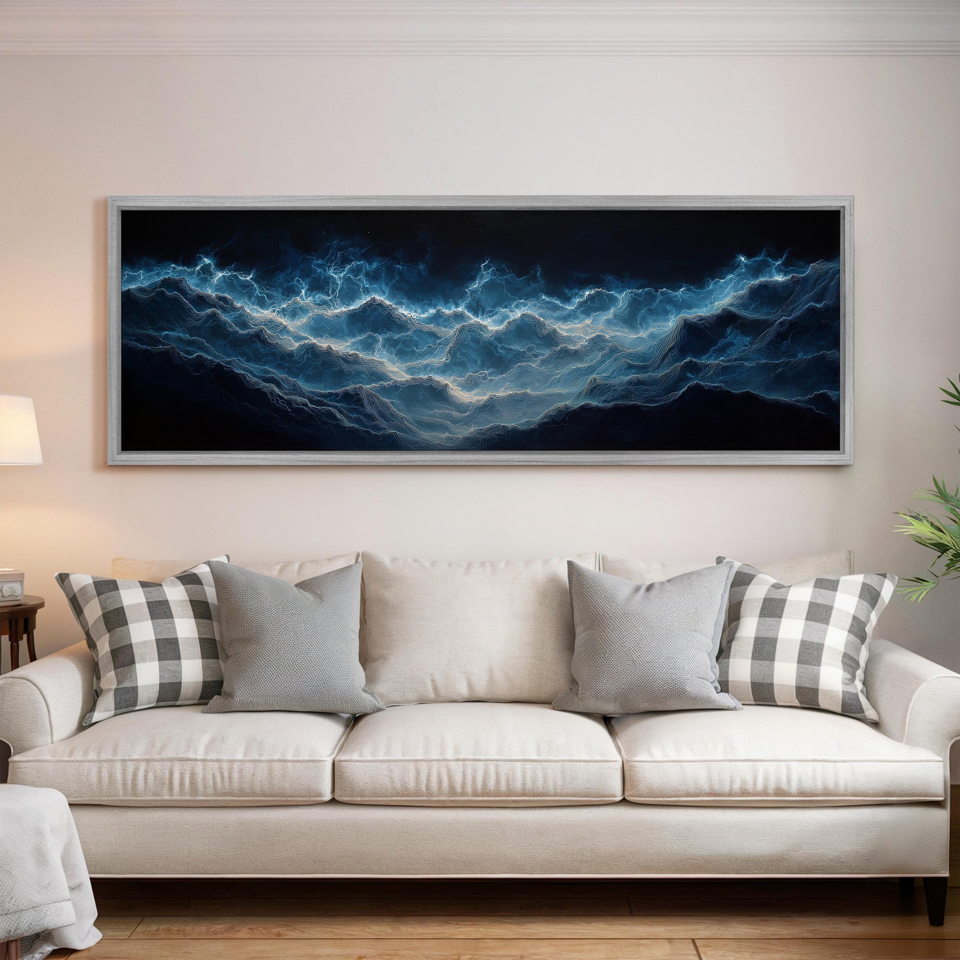 a large, framed painting of a dark blue ocean scene hanging on a white wall above a white couch with gray and white patterned pillows.