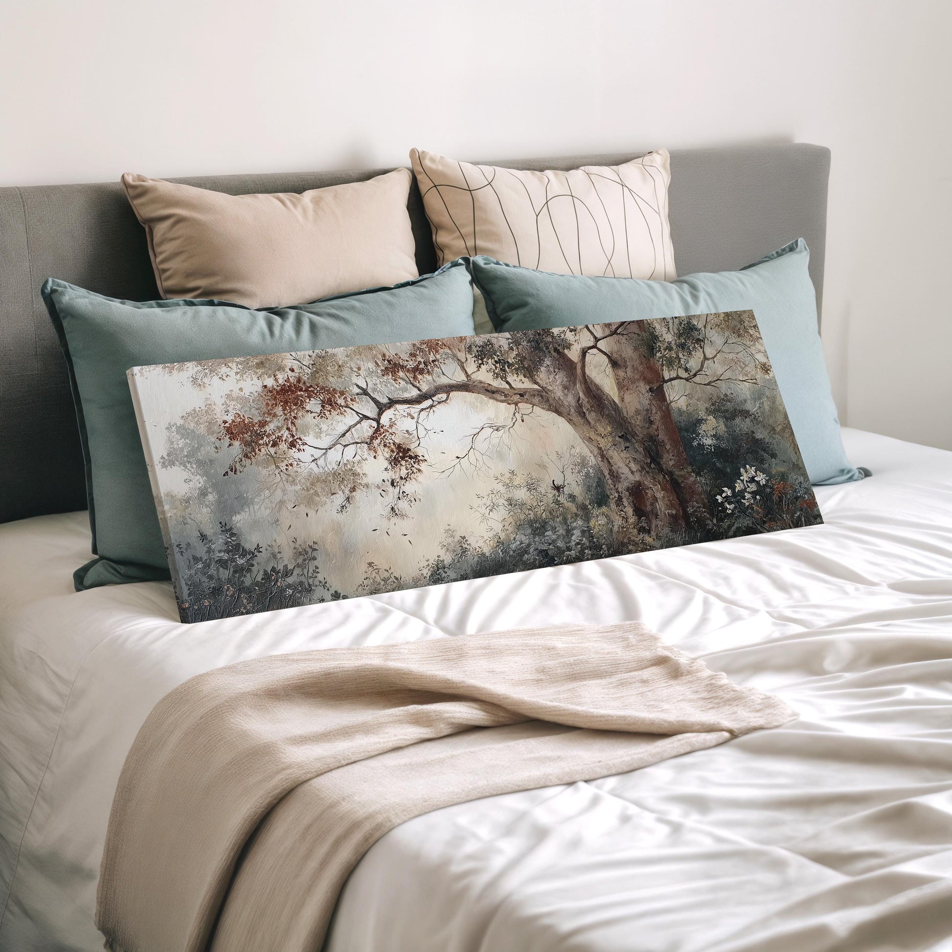 a bedroom with a bed covered in white sheets and a large painting of a tree on the bed. The painting is surrounded by multiple pillows, creating a cozy and inviting atmosphere.