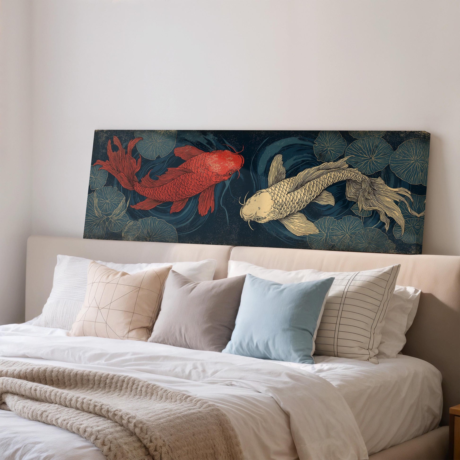 a large painting of two koi fish, one red and one gold, displayed on a wall above a bed with white pillows and a gray blanket.