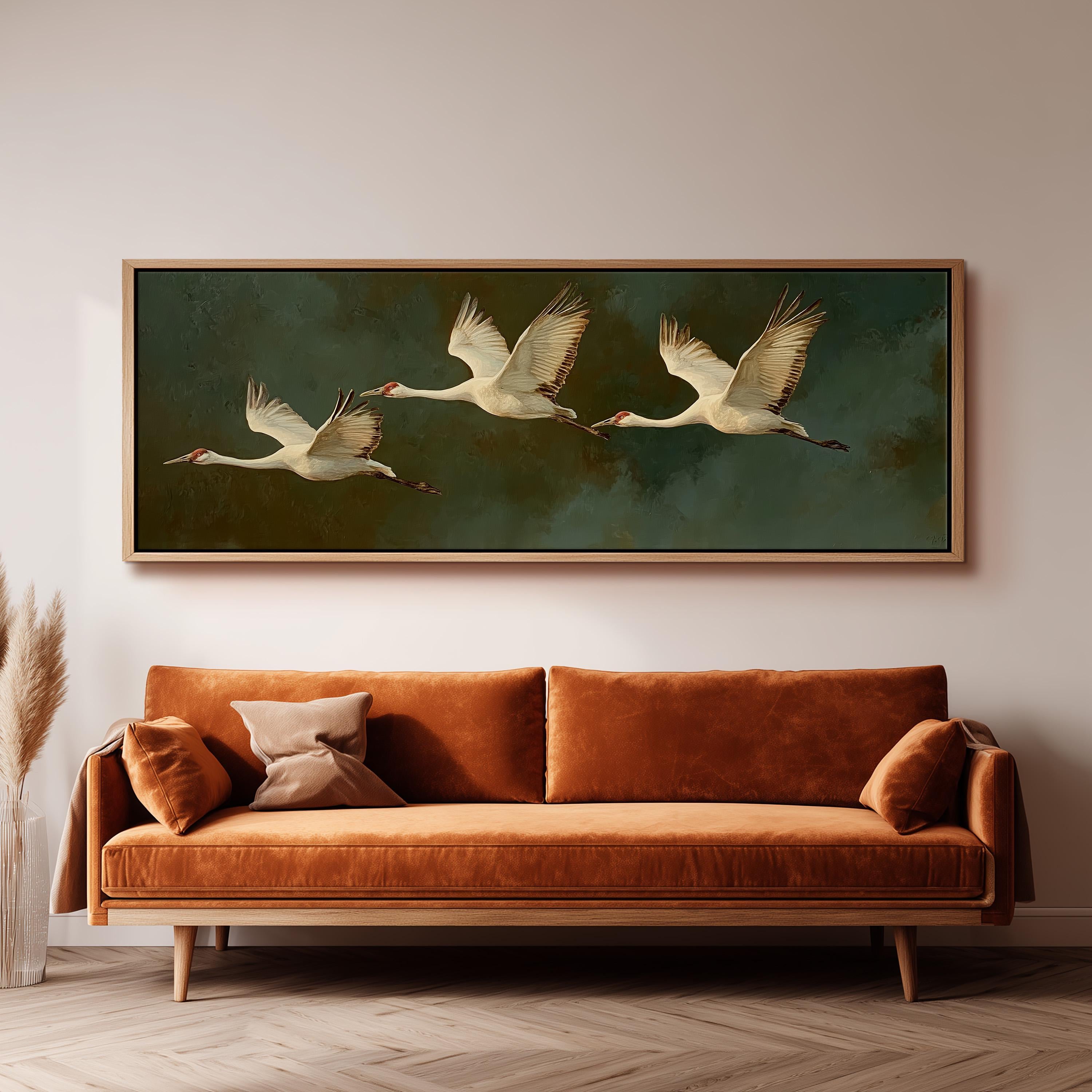 a large painting of three white birds in flight, hanging on a wall above a brown sofa.