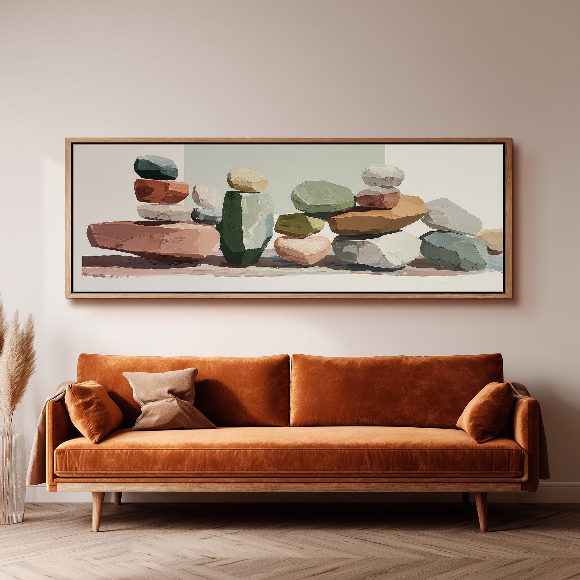 a large, abstract painting of stacked rocks and boulders hanging on a wall above a brown sofa with a wooden frame.