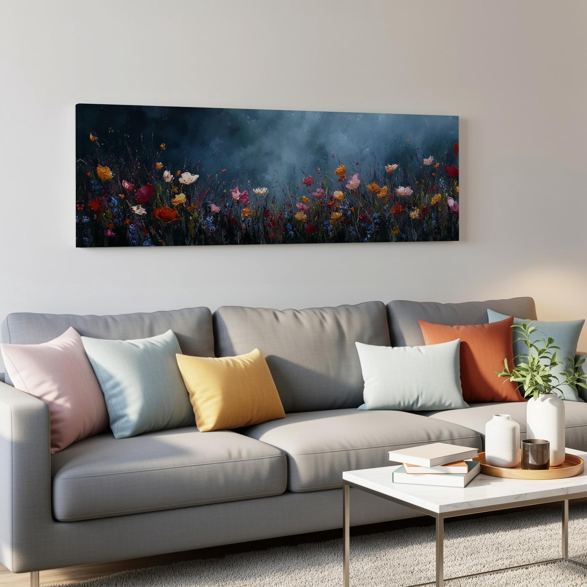 a gray couch with colorful throw pillows, a coffee table, and a painting of a field of flowers hanging on the wall above it.