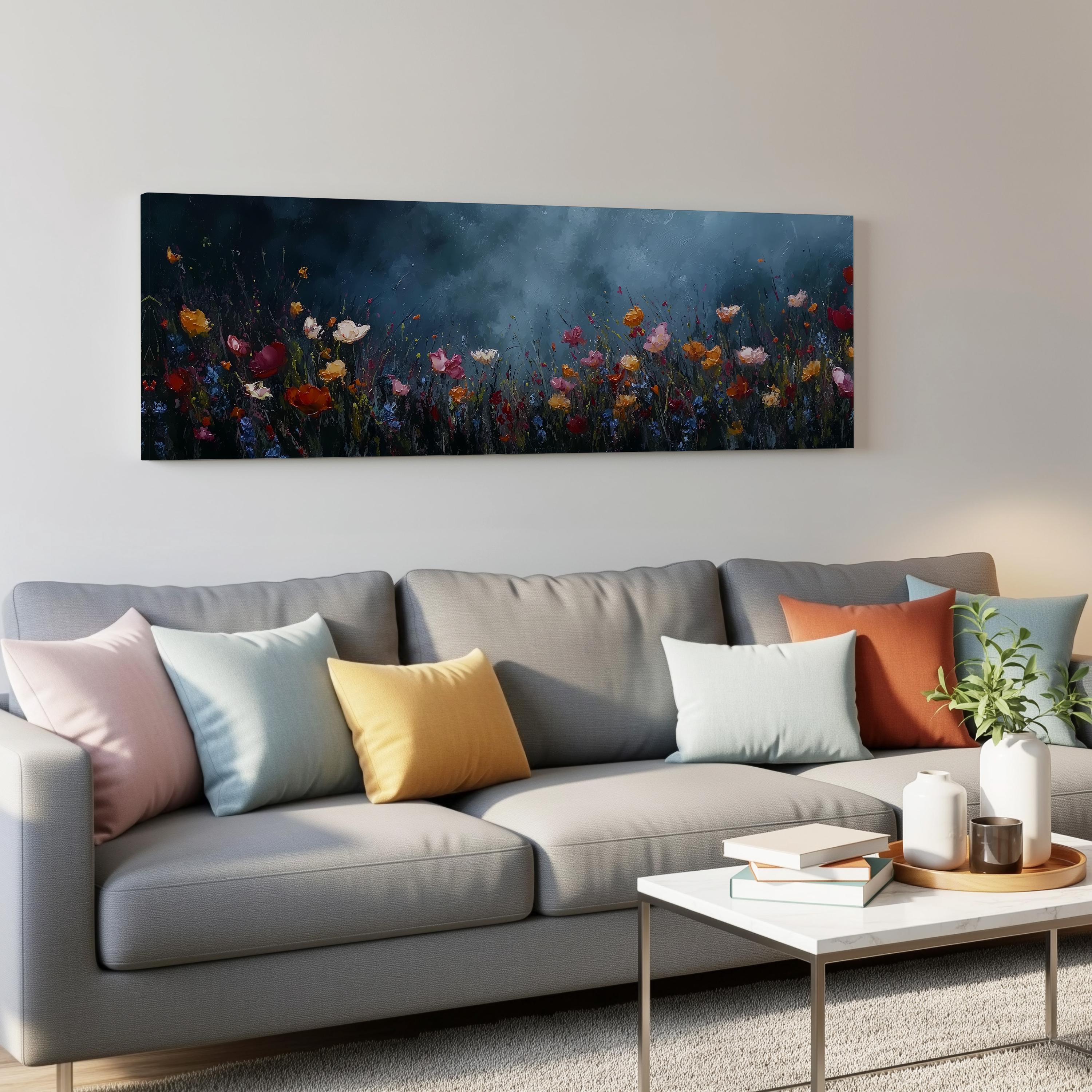 a gray couch with colorful throw pillows, a coffee table, and a painting of a field of flowers hanging on the wall above it.