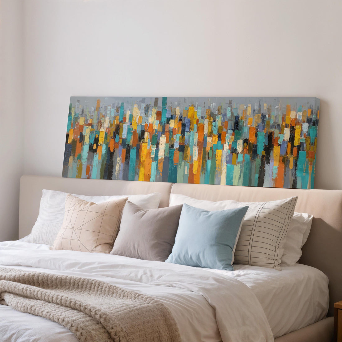 a large abstract painting hanging on a wall above a bed with white pillows and a gray headboard.