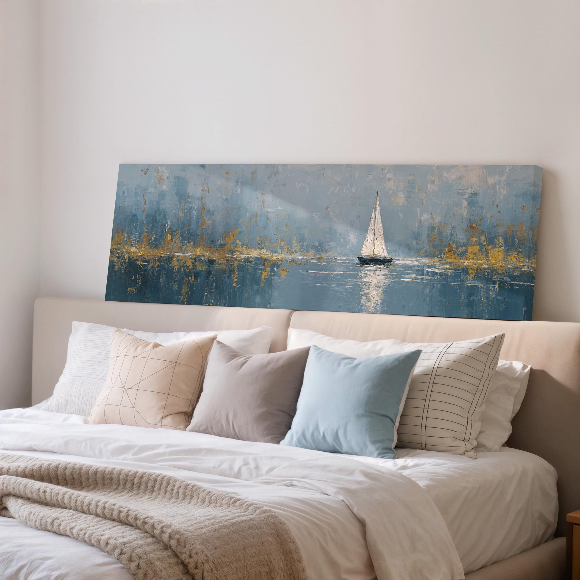 a large painting of a sailboat on a body of water, hanging on a wall above a bed with white pillows and a gray blanket.