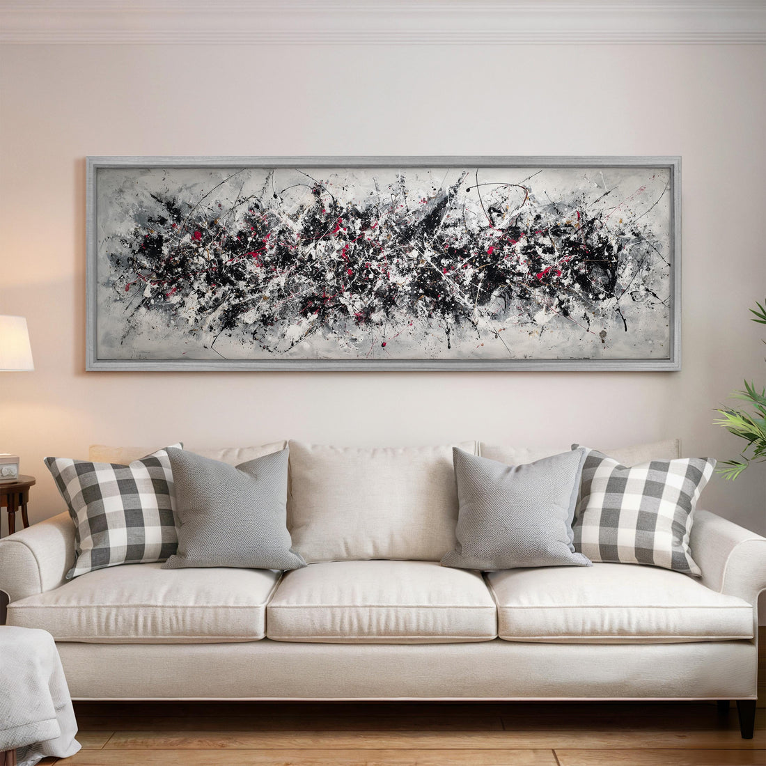 a large, abstract painting hanging on a wall above a white couch with gray and white patterned pillows.