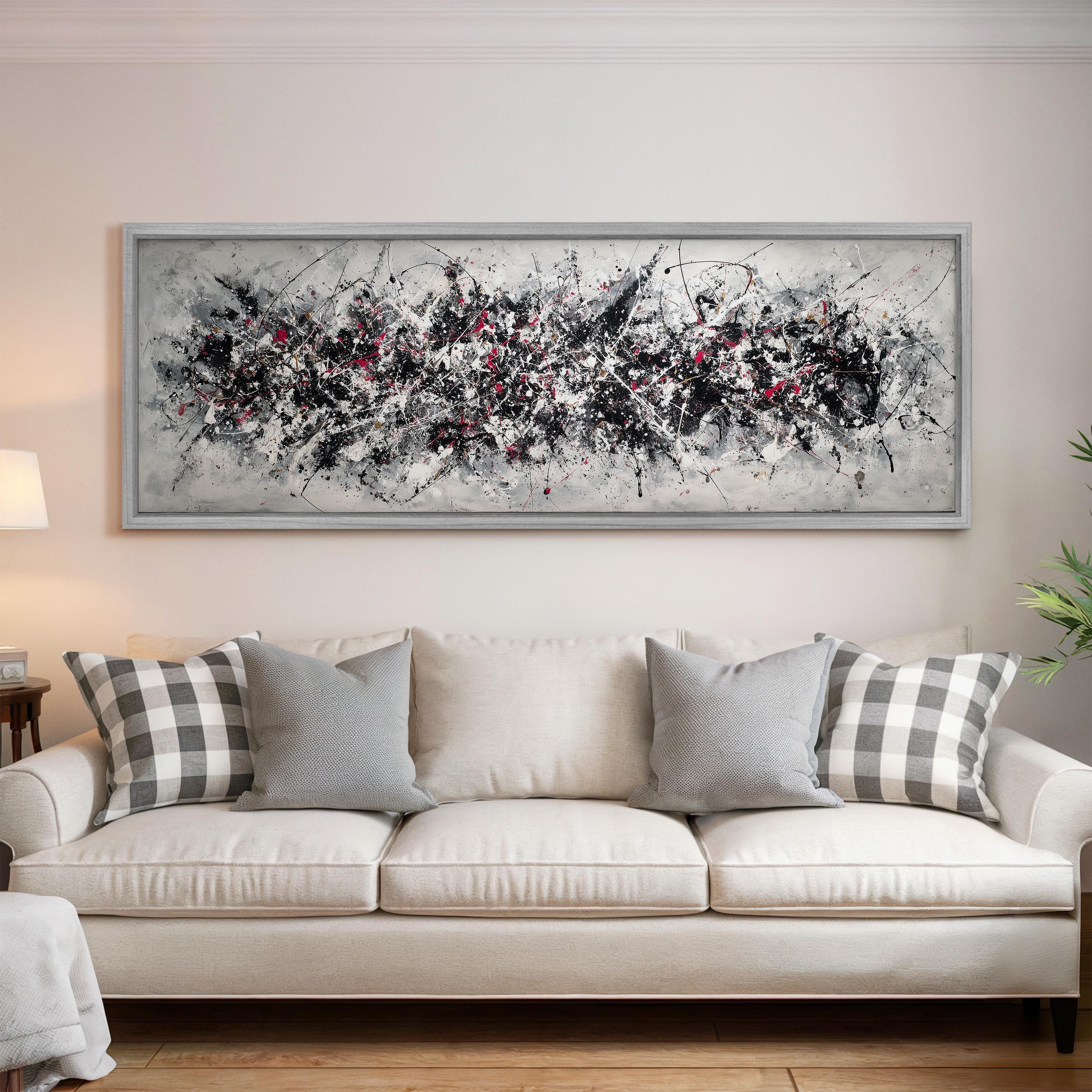 a large, abstract painting hanging on a wall above a white couch with gray and white patterned pillows.