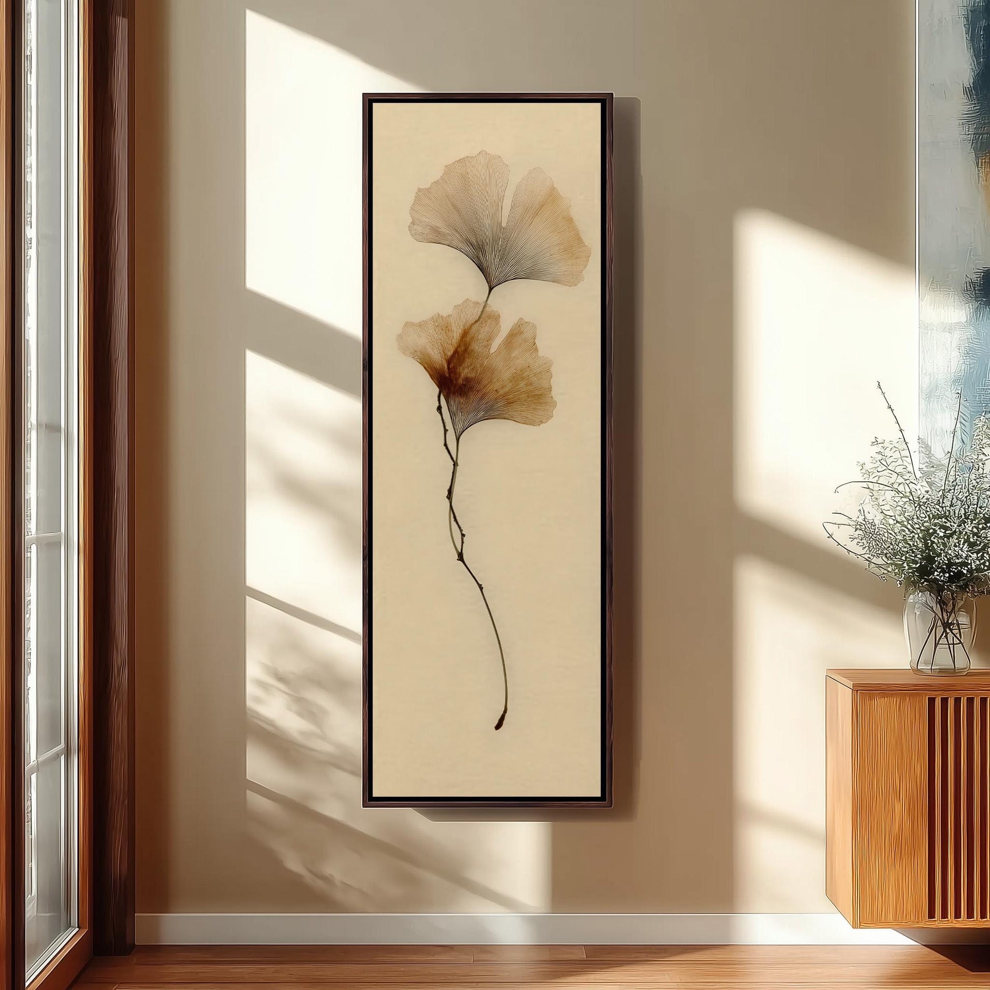 a framed artwork of two large, delicate flowers hanging on a wall in a room with a wooden floor and a window.
