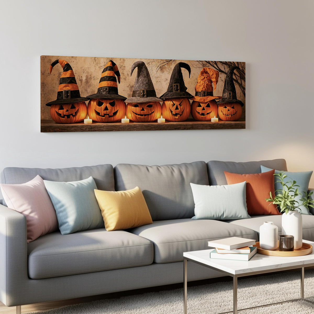 Jack-o'-lanterns wearing witch hats by candlelight panoramic canvas print above a grey sofa in a living room