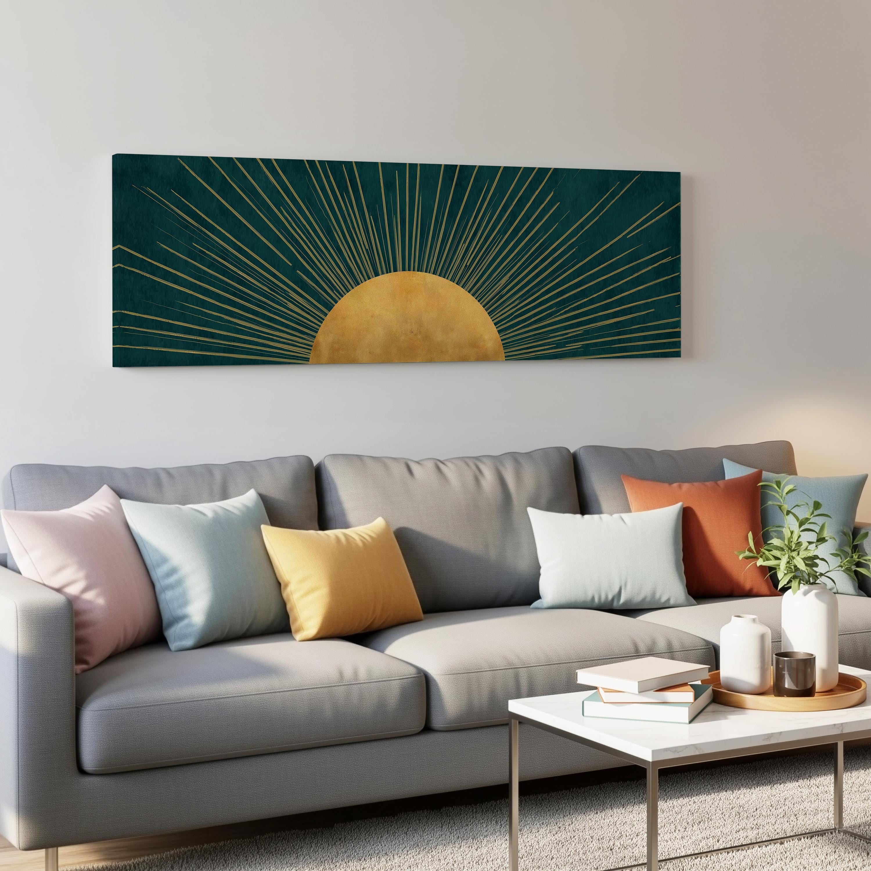 a modern living room with a gray sofa adorned with colorful throw pillows. Above the sofa, a large abstract painting of a sun with a golden center is displayed on the wall. The room also includes a coffee table with books and a plant, creating a cozy and inviting atmosphere.