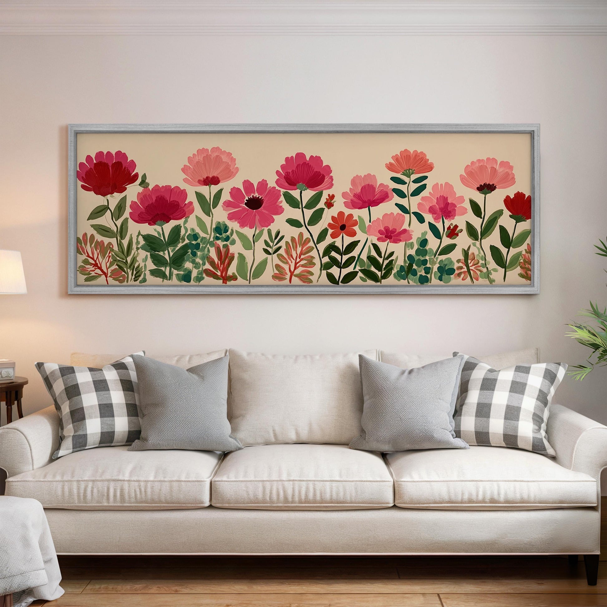 a large framed print of a floral design hanging on a wall above a white sofa with gray and white plaid throw pillows.