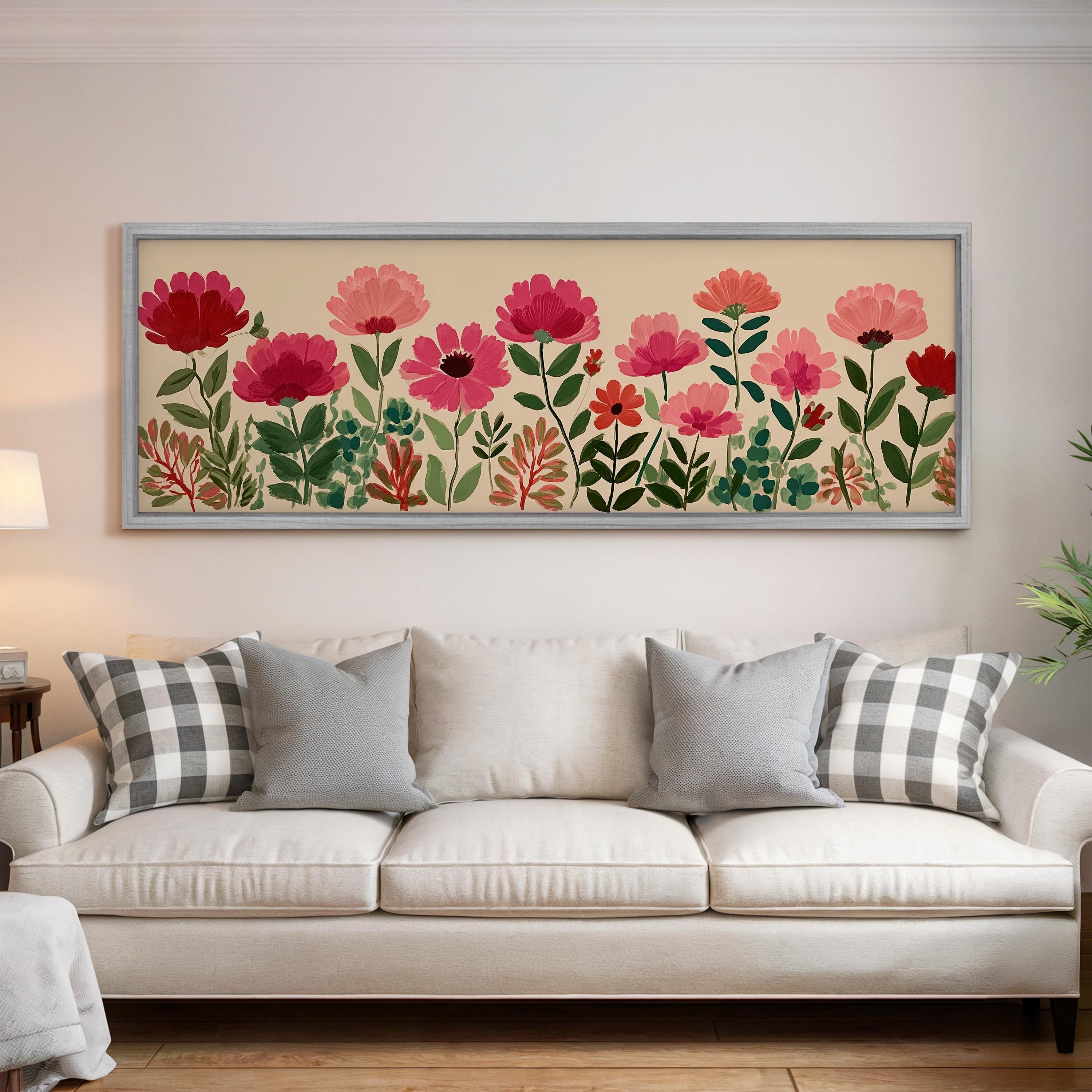 a large framed print of a floral design hanging on a wall above a white sofa with gray and white plaid throw pillows.