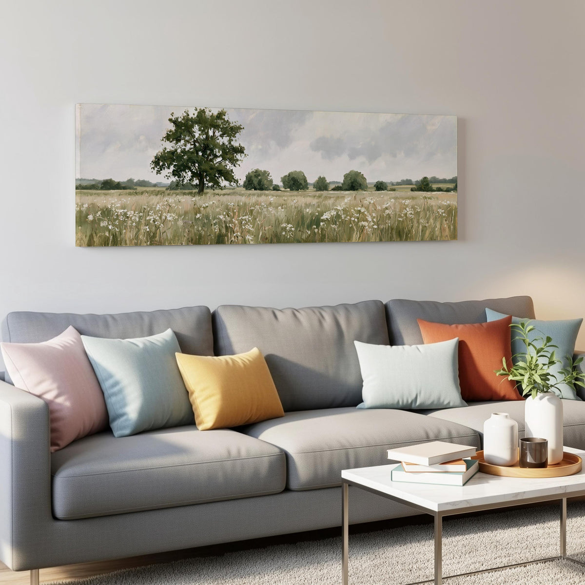 Lone oak tree in a daisy meadow panoramic canvas print above a grey sofa in a living room