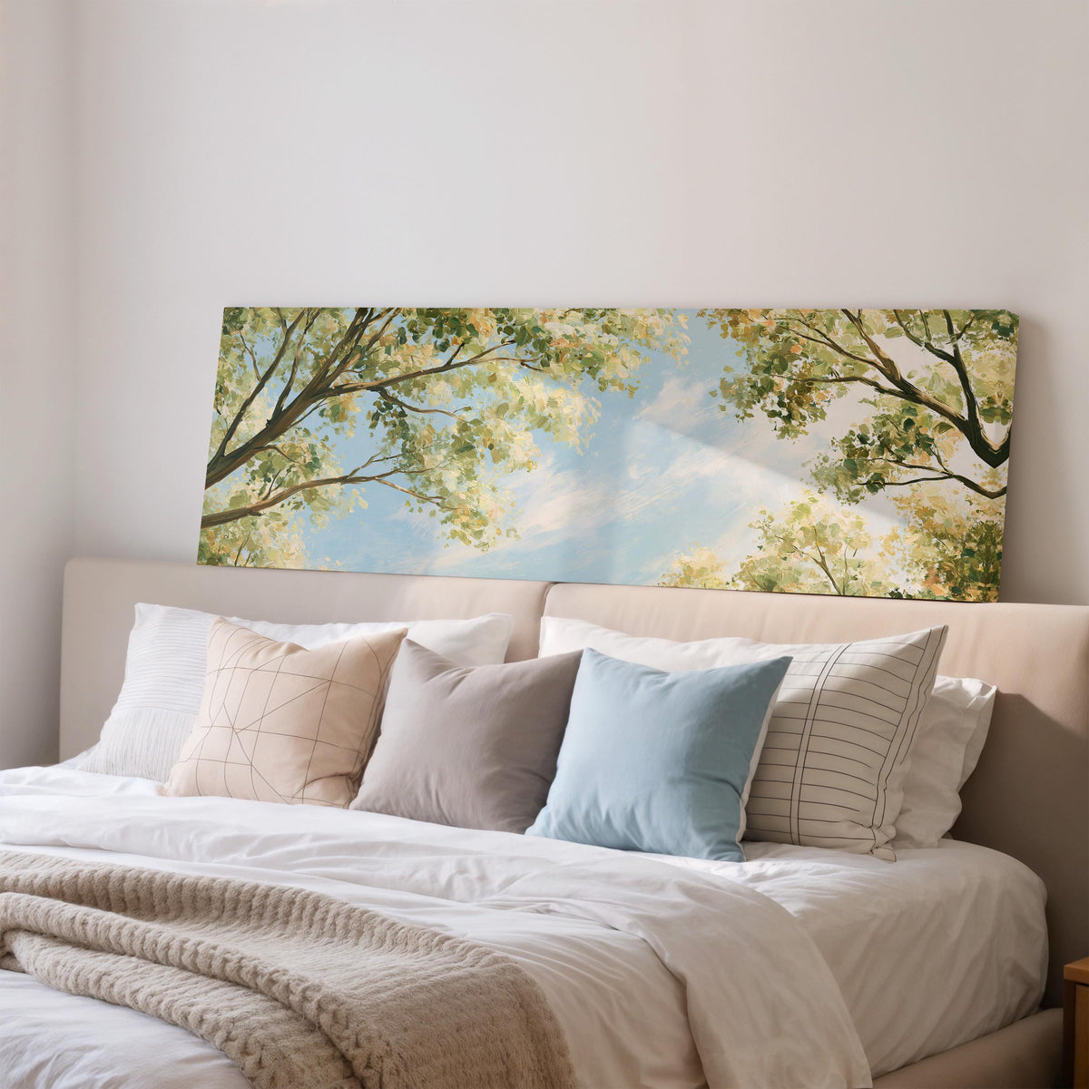 Sunlit leafy branches framing soft clouds wide panoramic canvas print above a bed in a bedroom