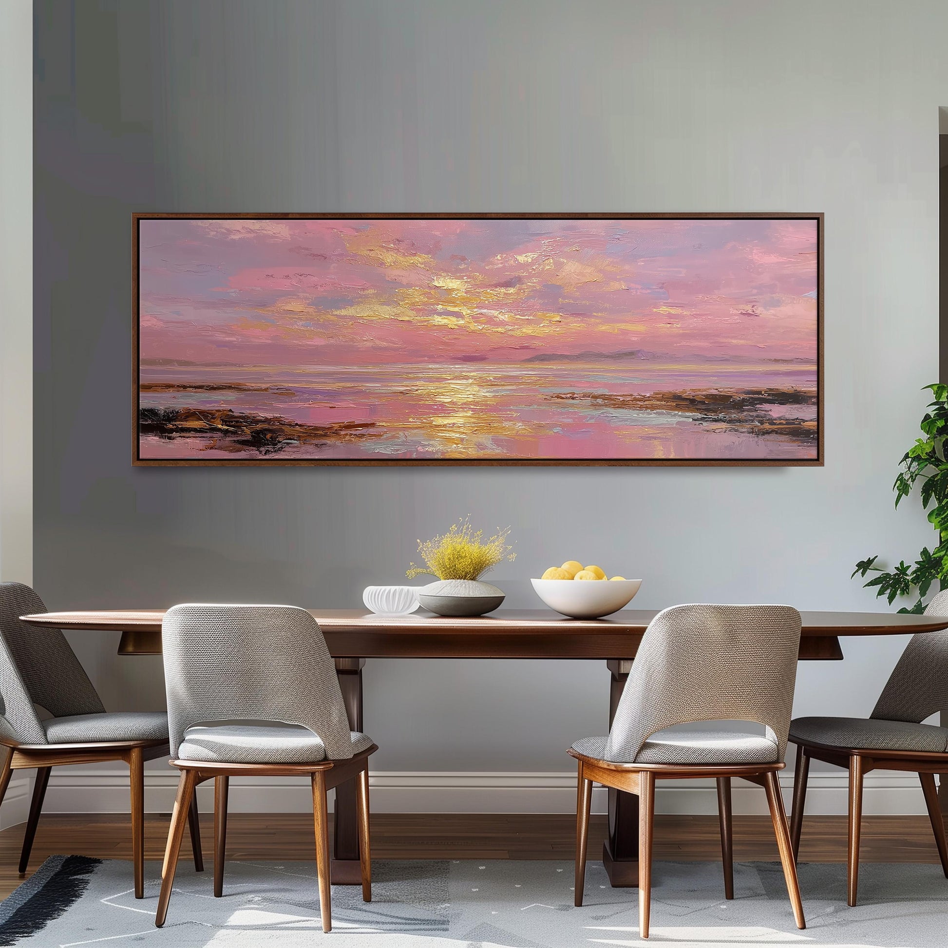 a large painting of a sunset over a body of water, hanging on a wall above a wooden dining table with four chairs. The painting is framed and appears to be the focal point of the room.
