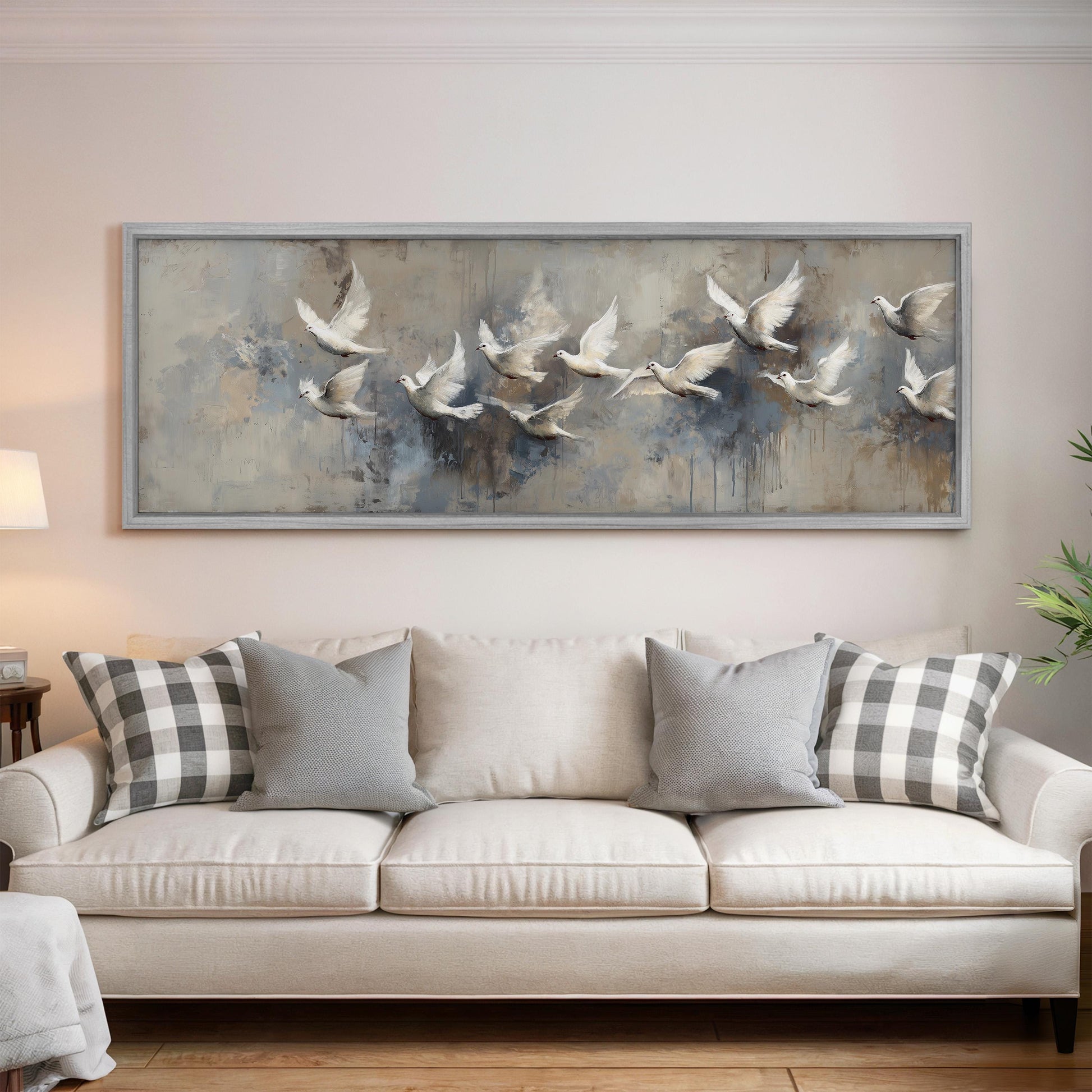 a large painting of a flock of white birds in flight, hanging on a wall above a white sofa with gray and white patterned throw pillows.