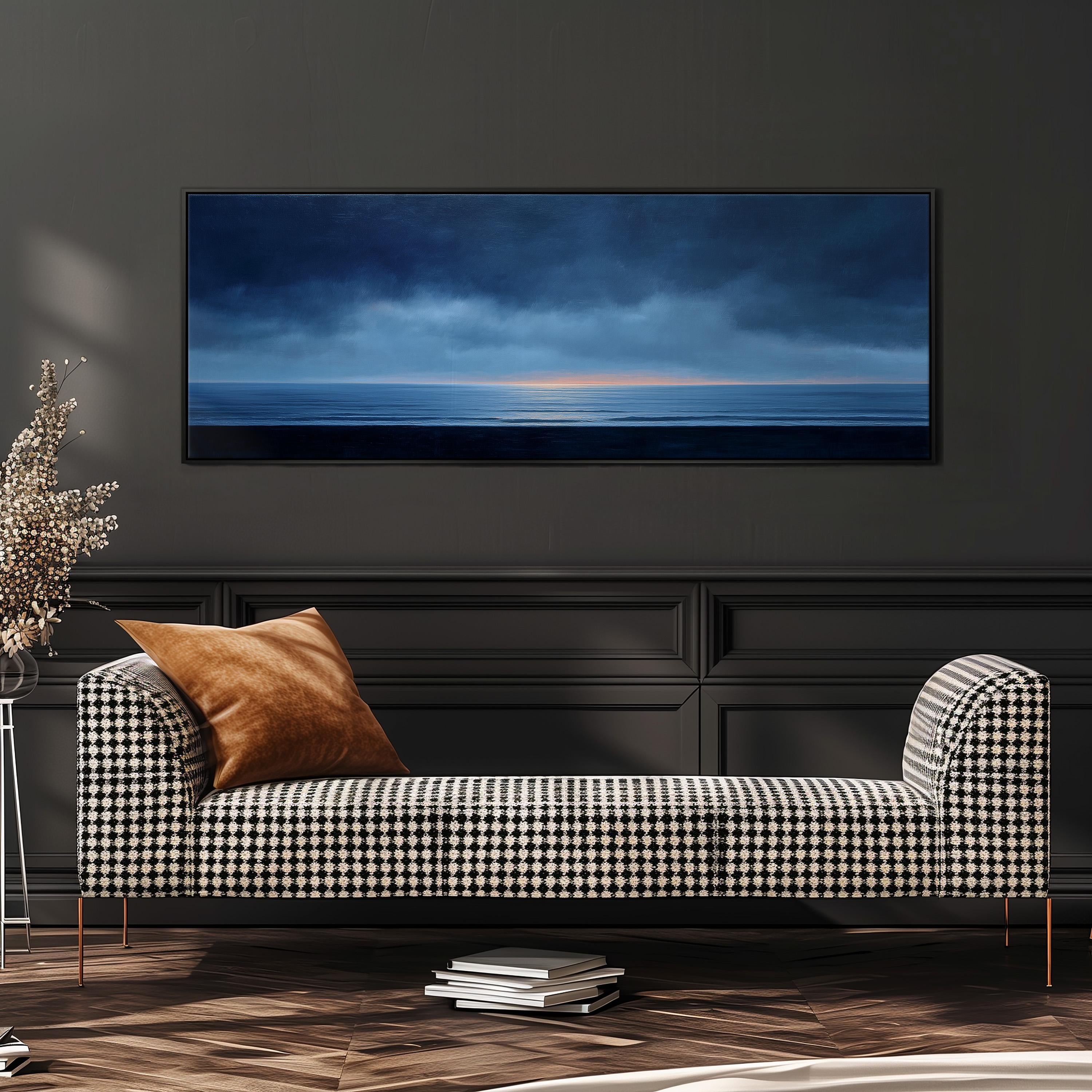 a black and white checkered sofa with a brown throw pillow, positioned in front of a large framed painting depicting a serene landscape with a body of water and a cloudy sky.