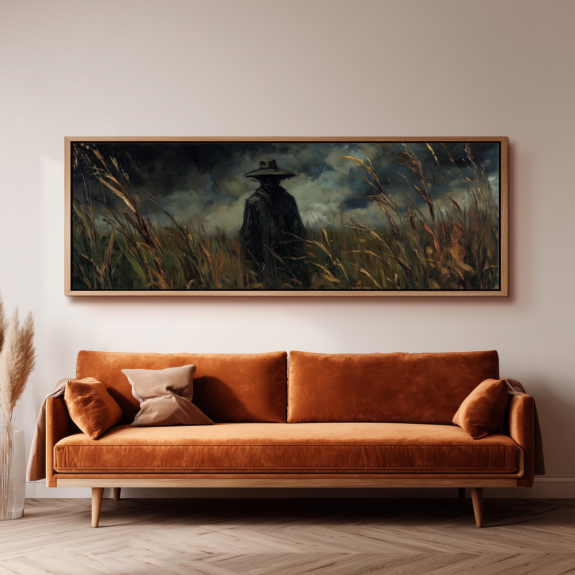 a large painting of a person in a hat standing in a field of tall grass, hanging on a wall above a brown sofa.