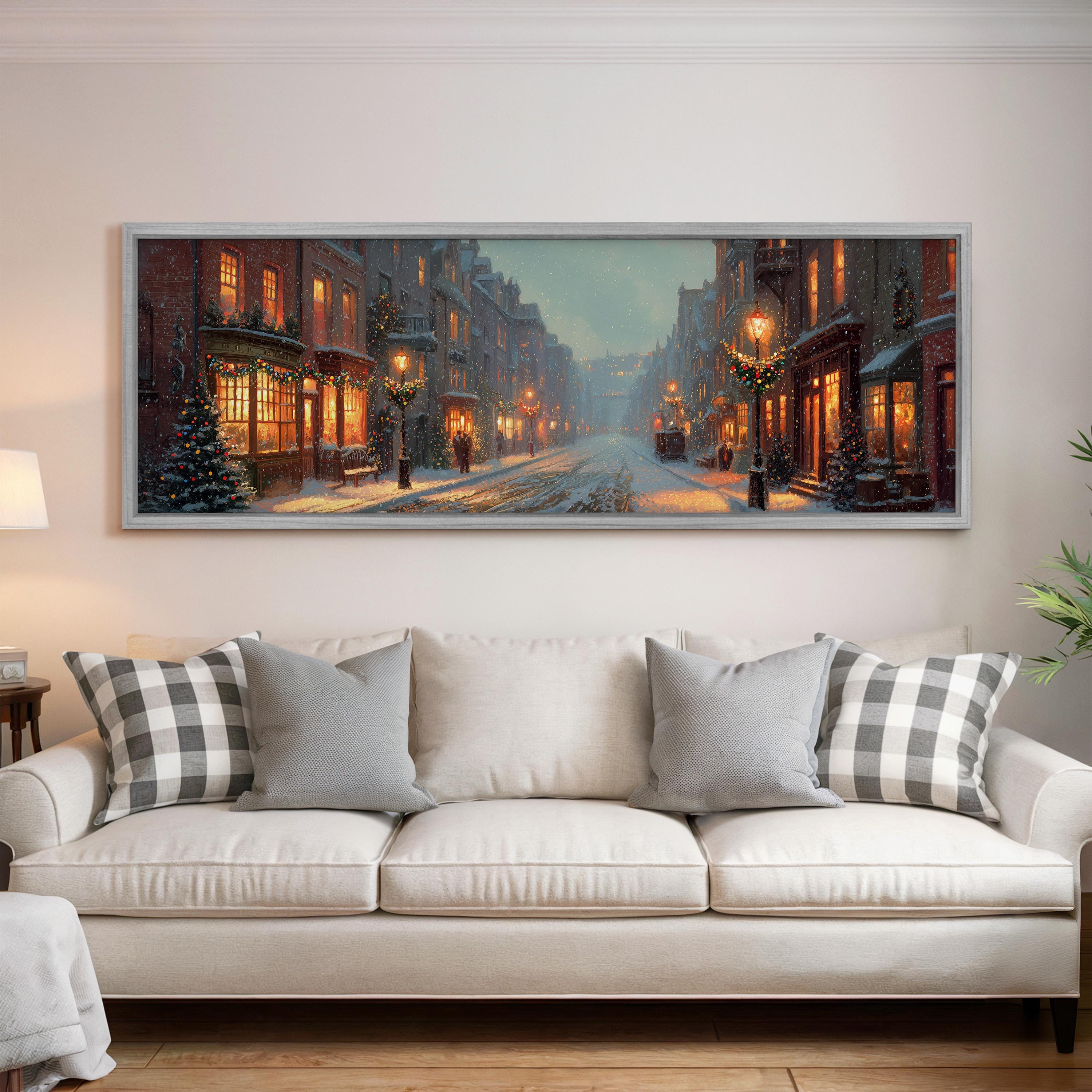 A large, framed painting depicting a snowy city street at night, with buildings, street lamps, and Christmas decorations illuminated.