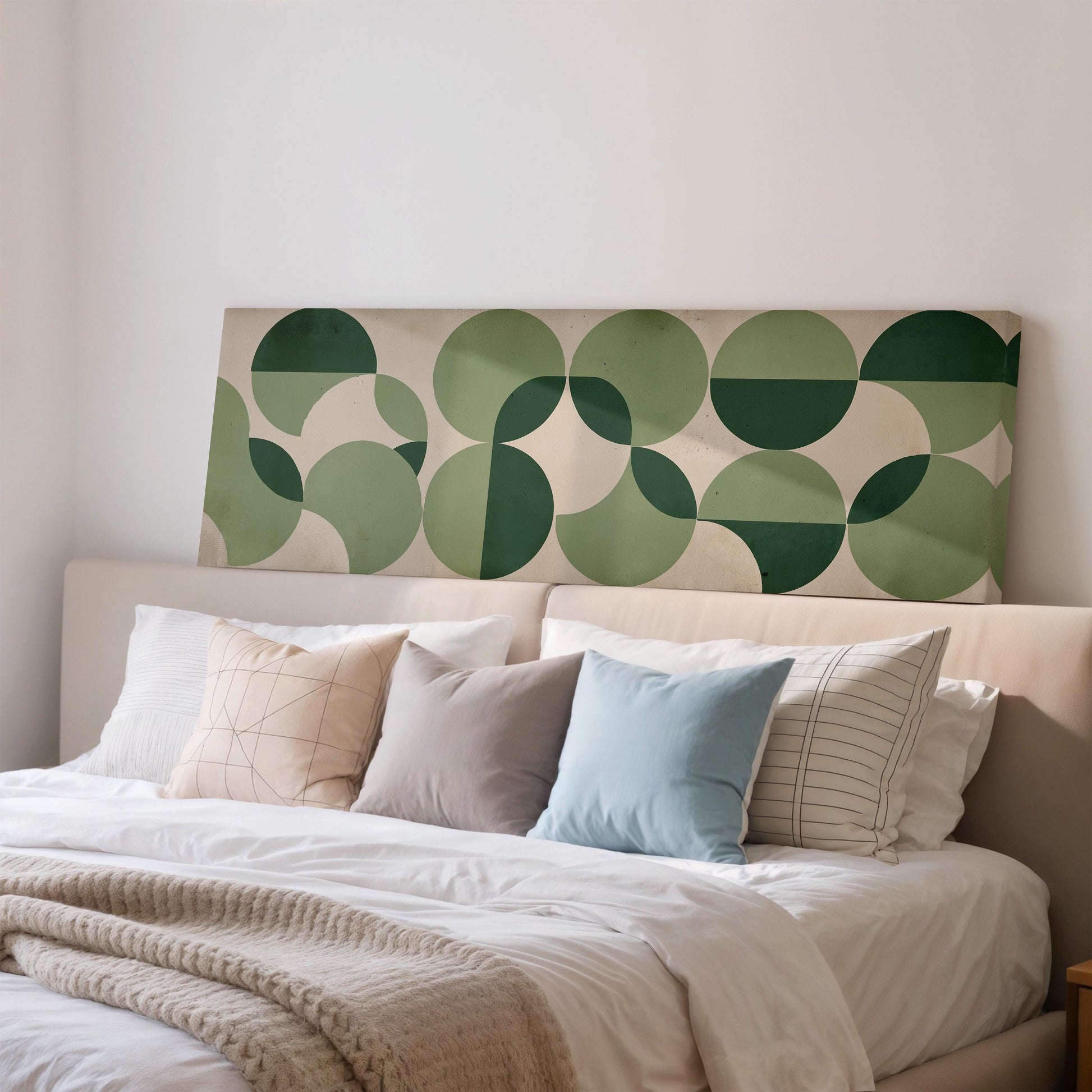 a neatly made bed with a variety of pillows and a blanket, set against a wall with a large, colorful geometric pattern.